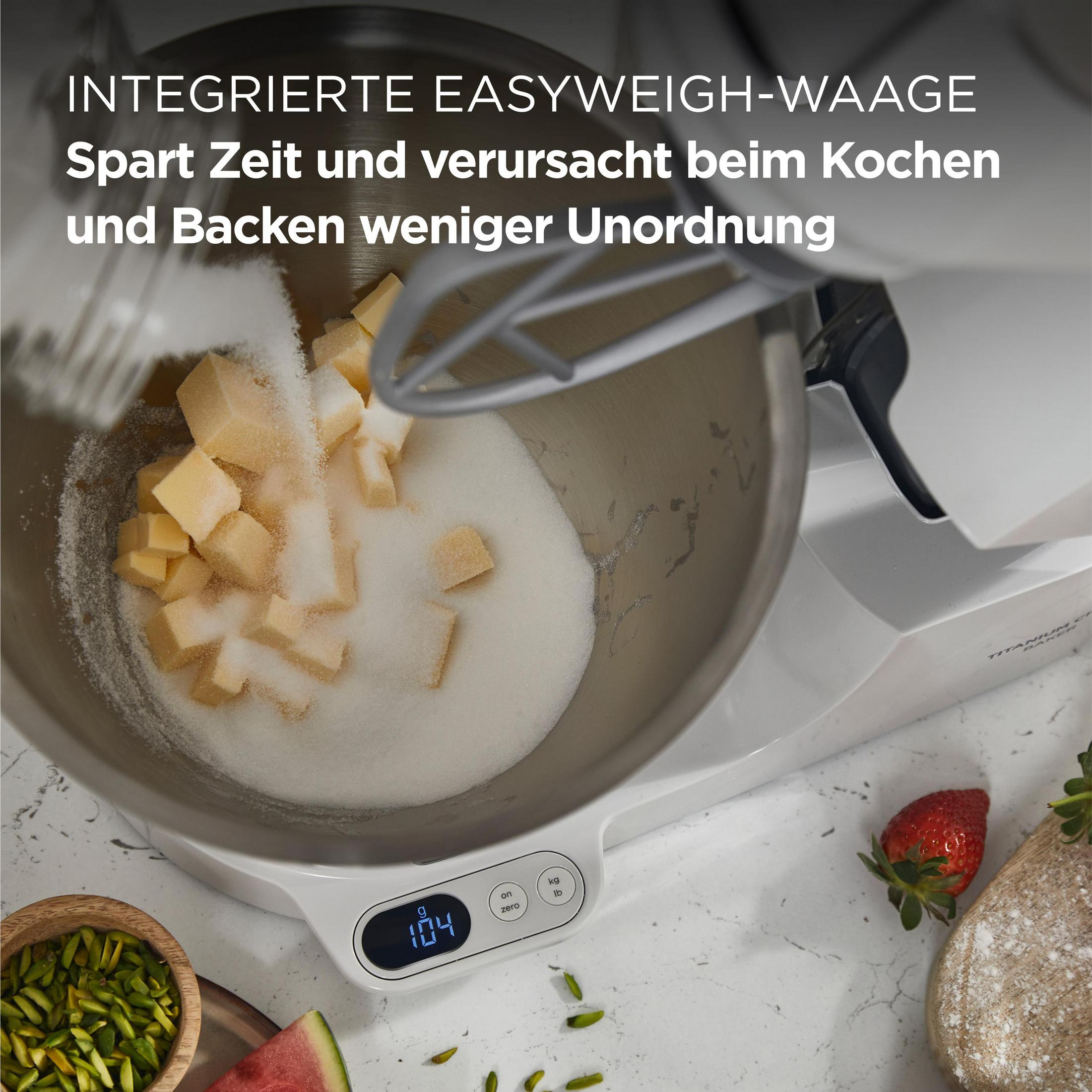 Küchenmixer, Butter und Zucker werden in die Schüssel gegossen. Eine Erdbeere in der Nähe.