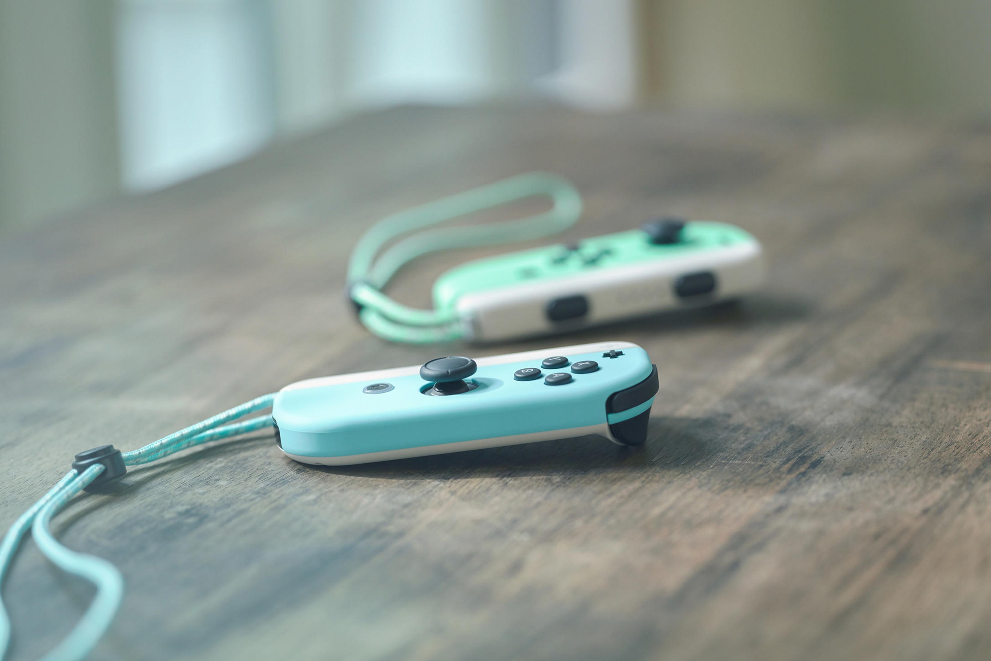 Zwei blaue und grüne Nintendo Switch Joy-Con-Controller auf einem Holztisch.