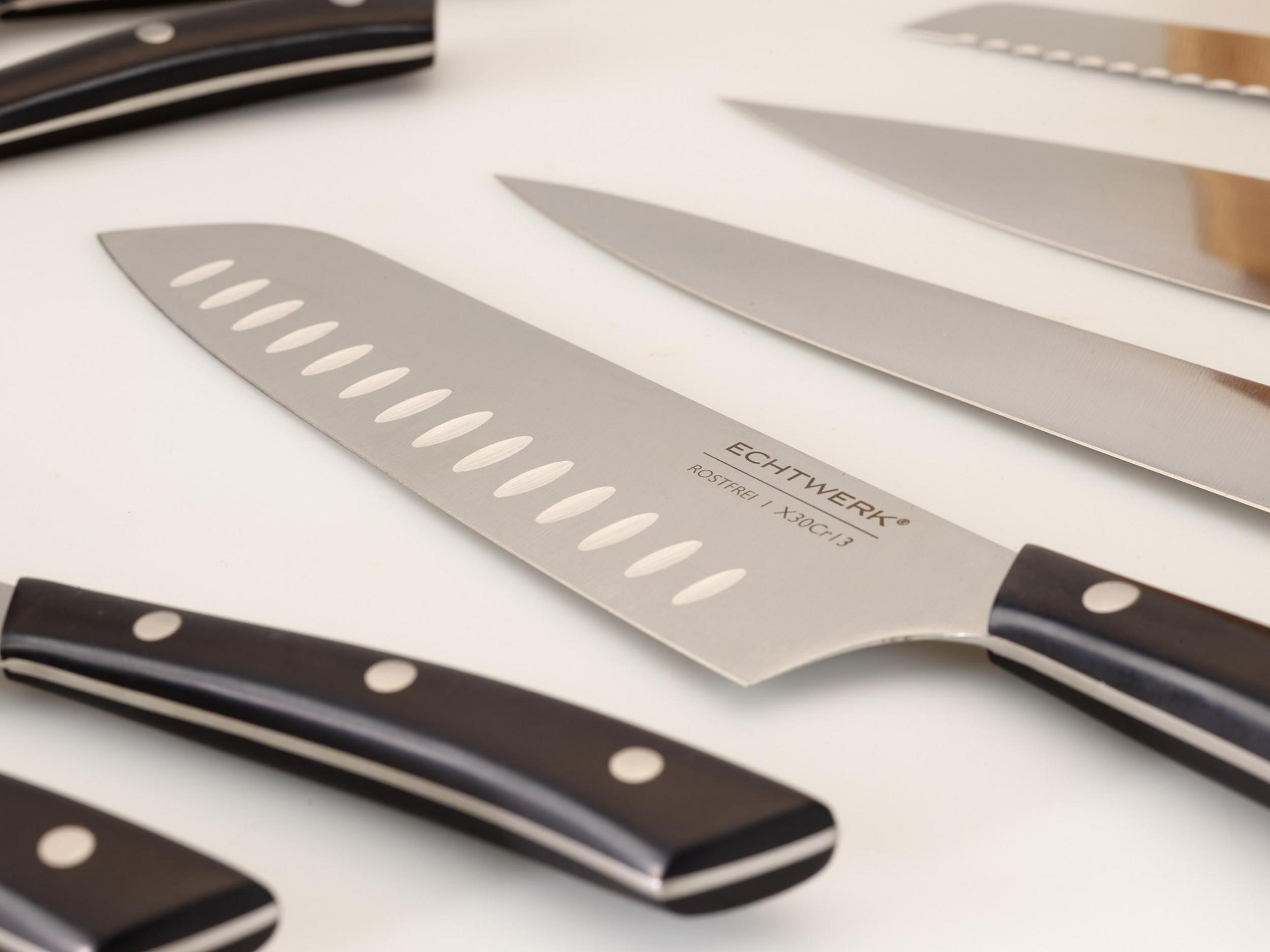 Mehrere Küchenmesser auf weißer Oberfläche. Die Messer haben schwarze Griffe und silberne Klingen.
