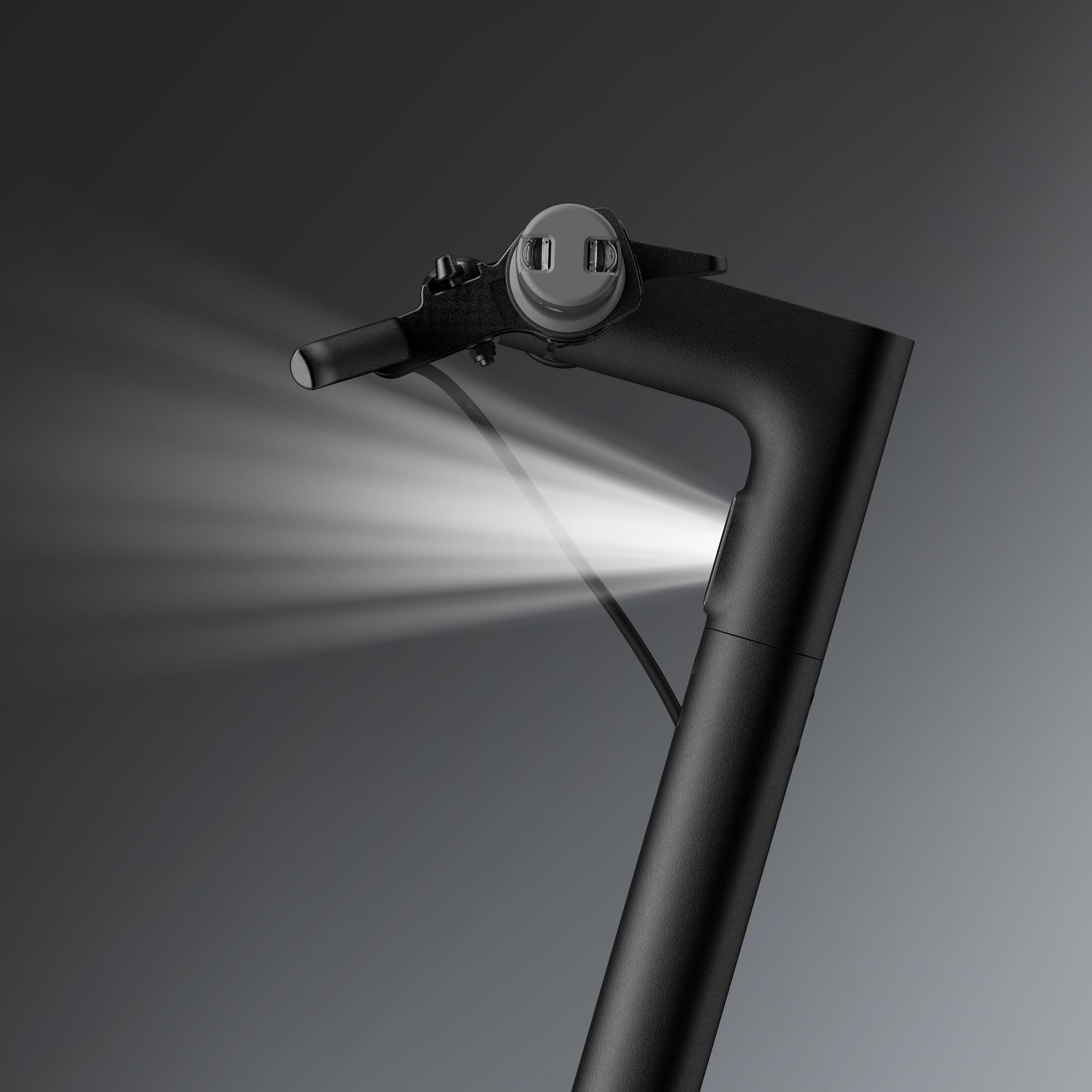 Ein schwarzer Rollerlenker mit leuchtendem Scheinwerfer. Der Hintergrund ist dunkel.