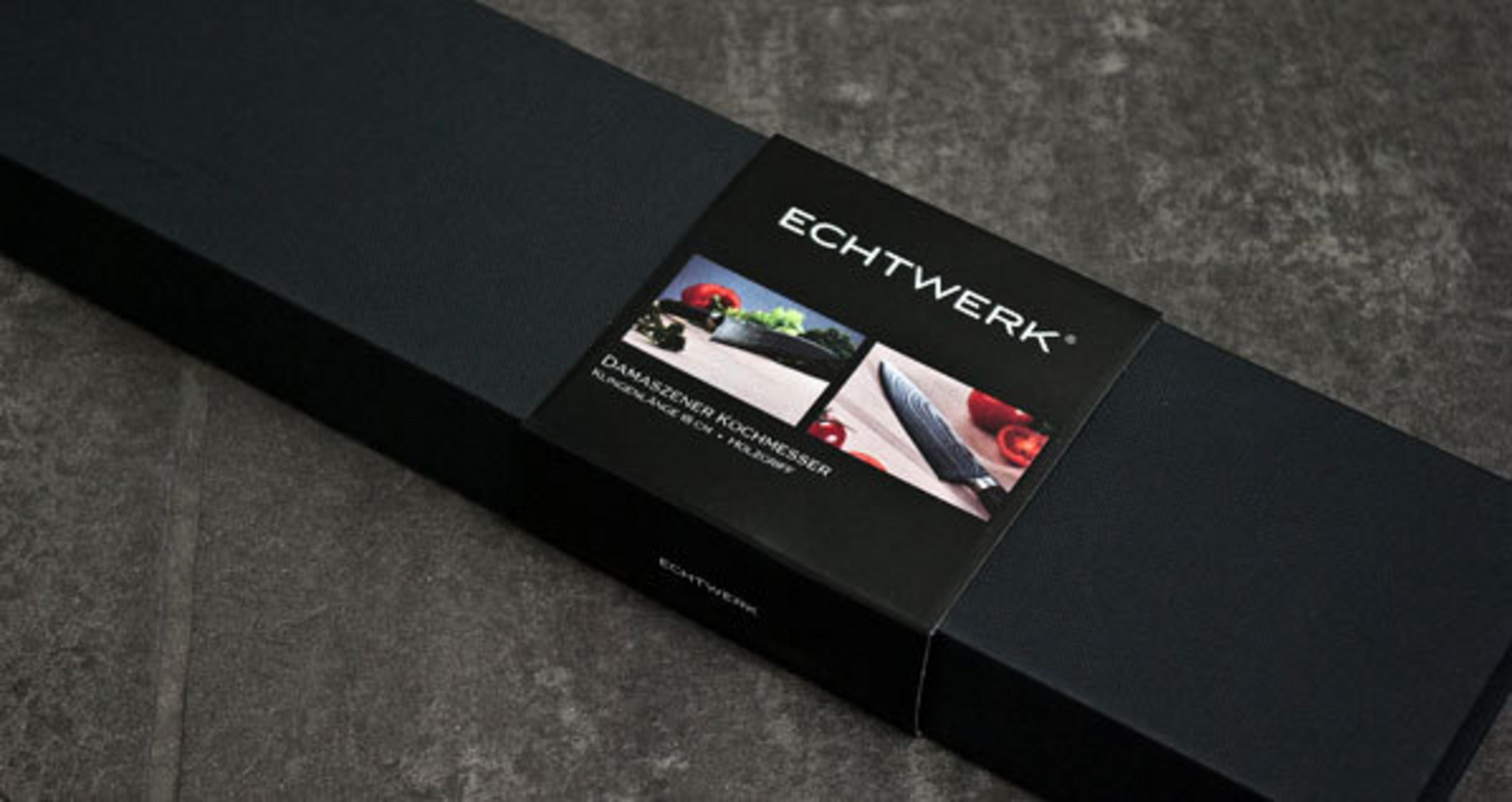 Schwarze Box mit Messer und Broschüre, auf dunkler Oberfläche.