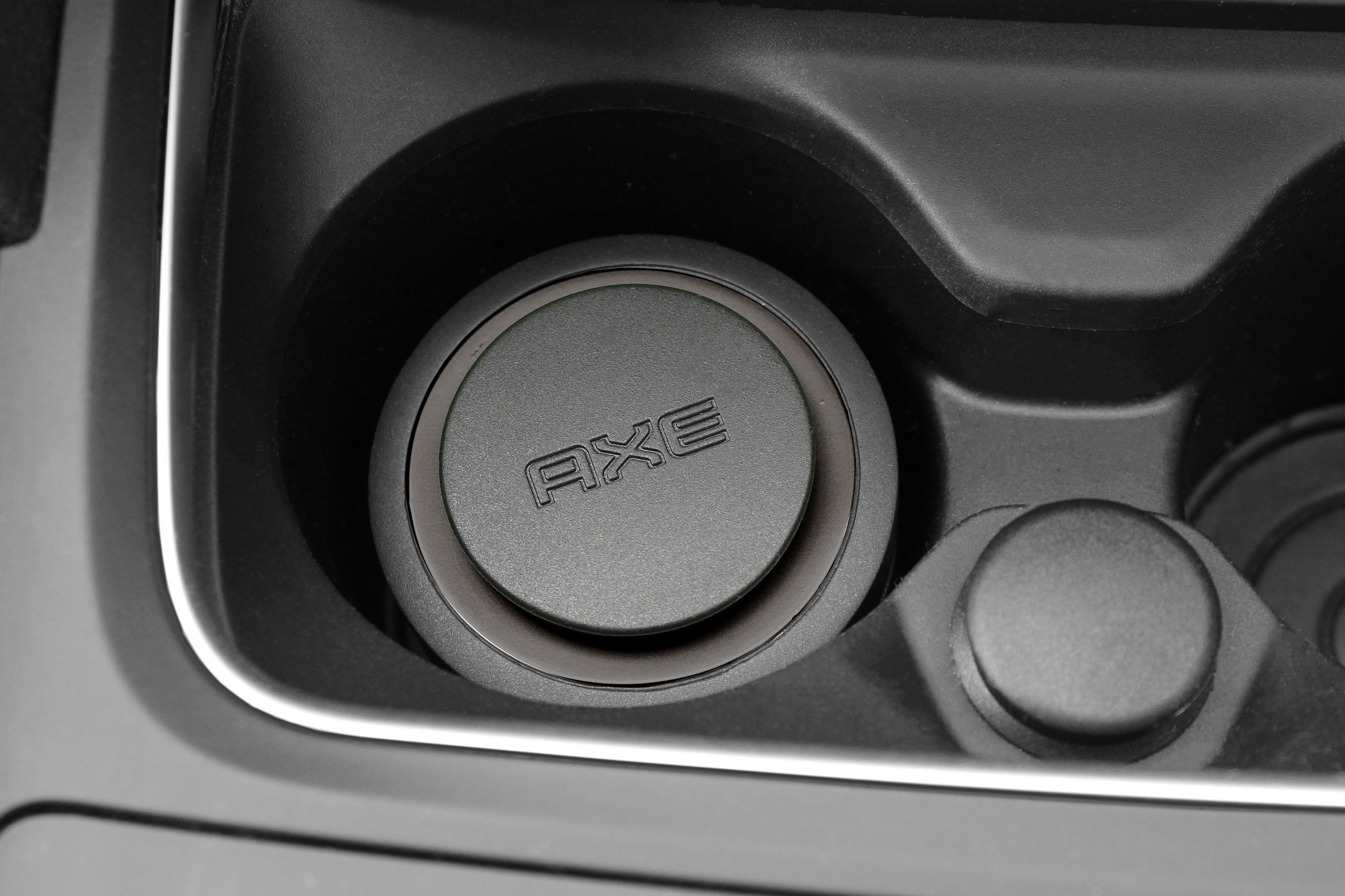 Ein Getränkehalter im Auto mit einem AXE Auto-Lufterfrischer darin.