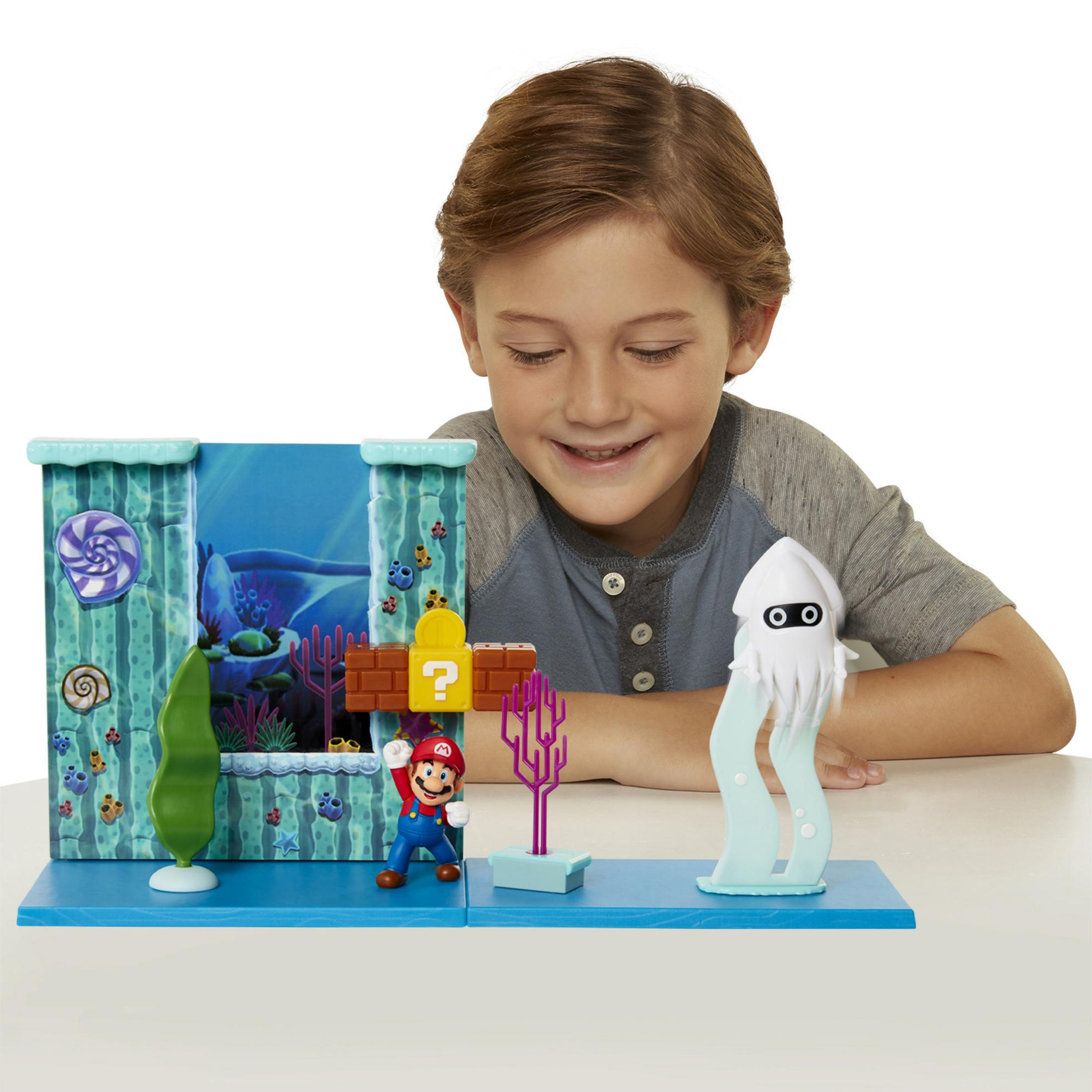 Junge betrachtet Mario-Spielset mit Mario-Figur, Blooper und aquatischem Hintergrund.