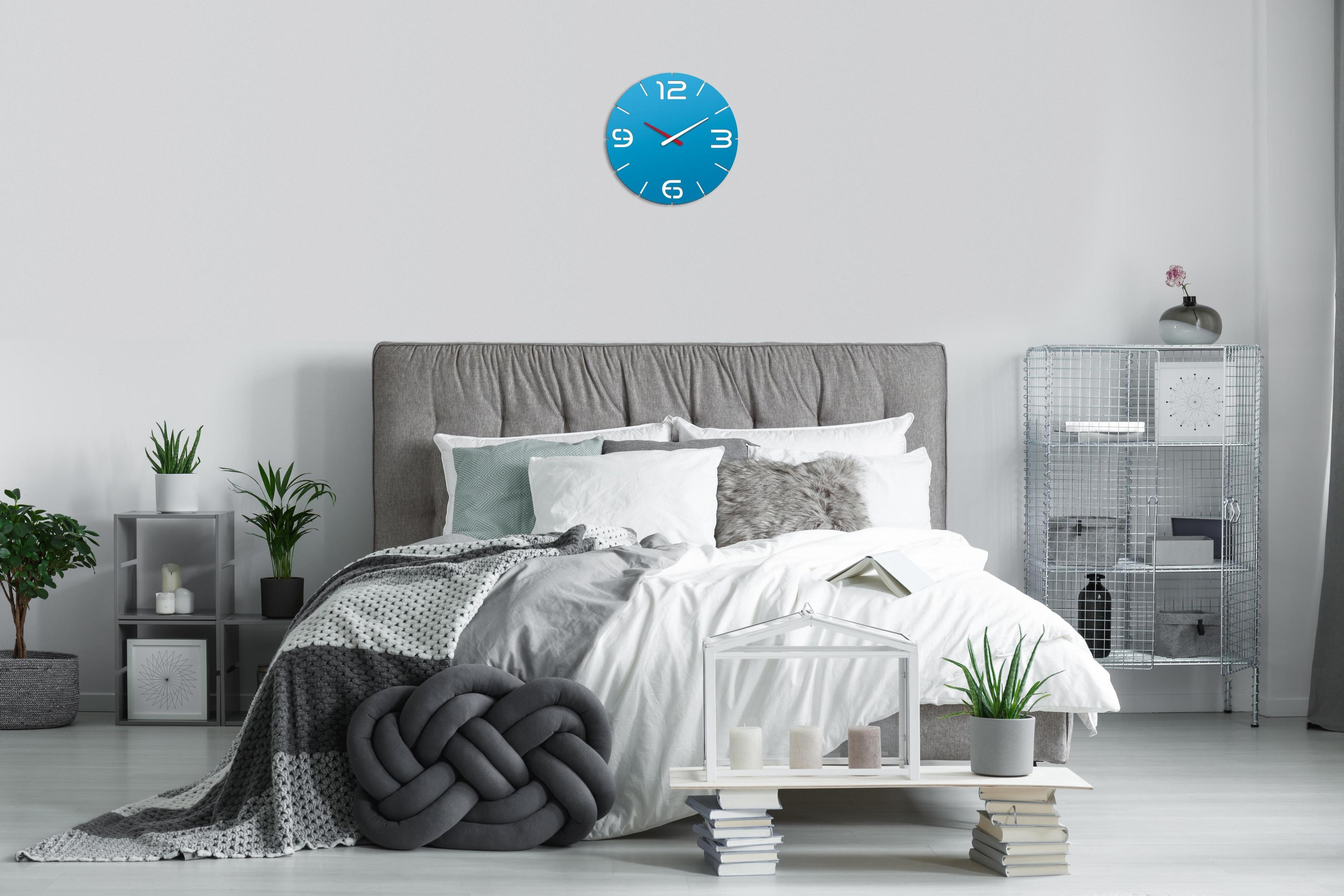 Schlafzimmer mit Bett, Uhr, Pflanzen und Beistelltisch.