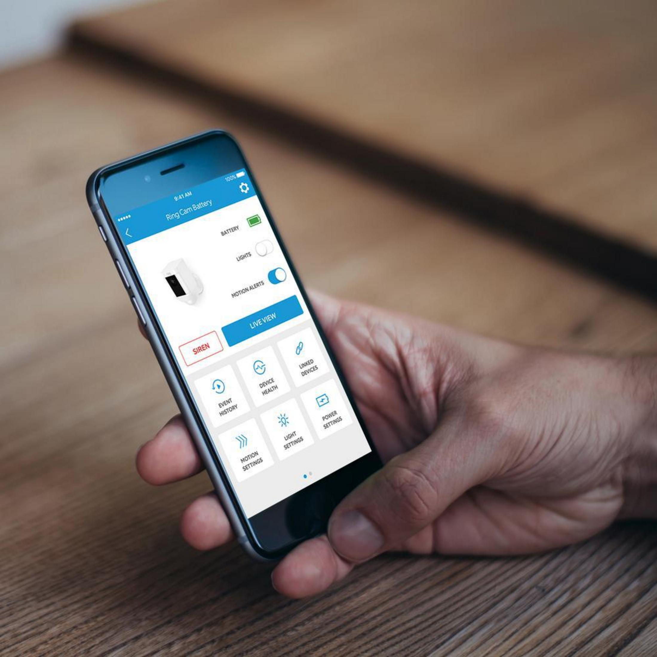 Osoba trzymająca smartfon z interfejsem aplikacji Ring Cam Battery.