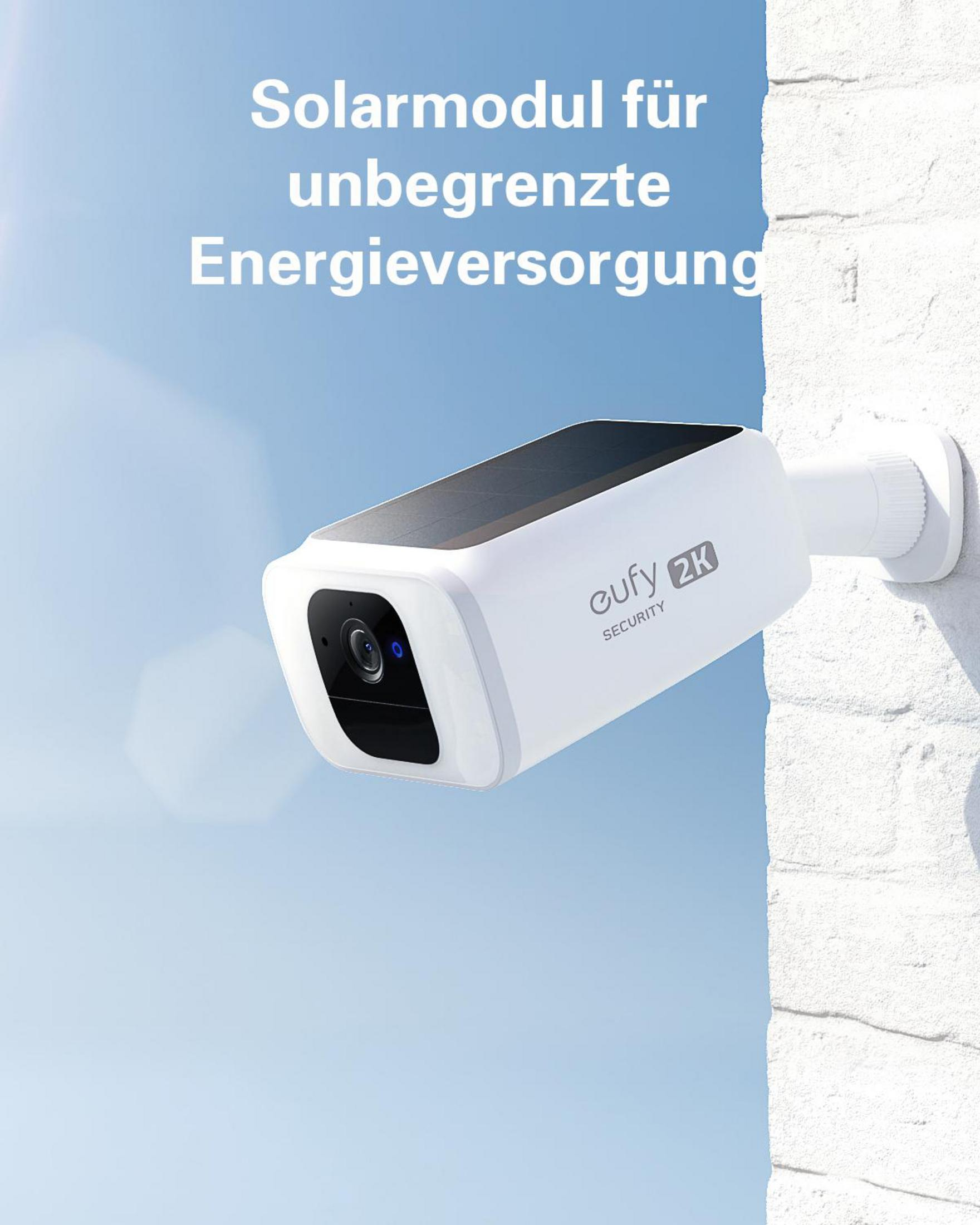White security camera with black panel and text 'eufy 2K SECURITY', mounted on a white brick wall, blue sky.