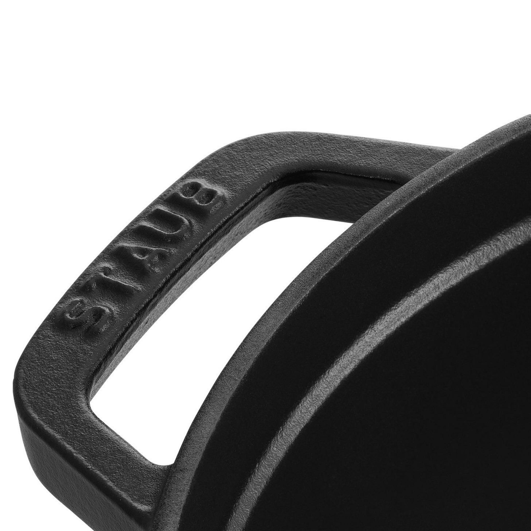 Gros plan sur une poignée de poêle en fonte noire avec la marque 'STAUB'.