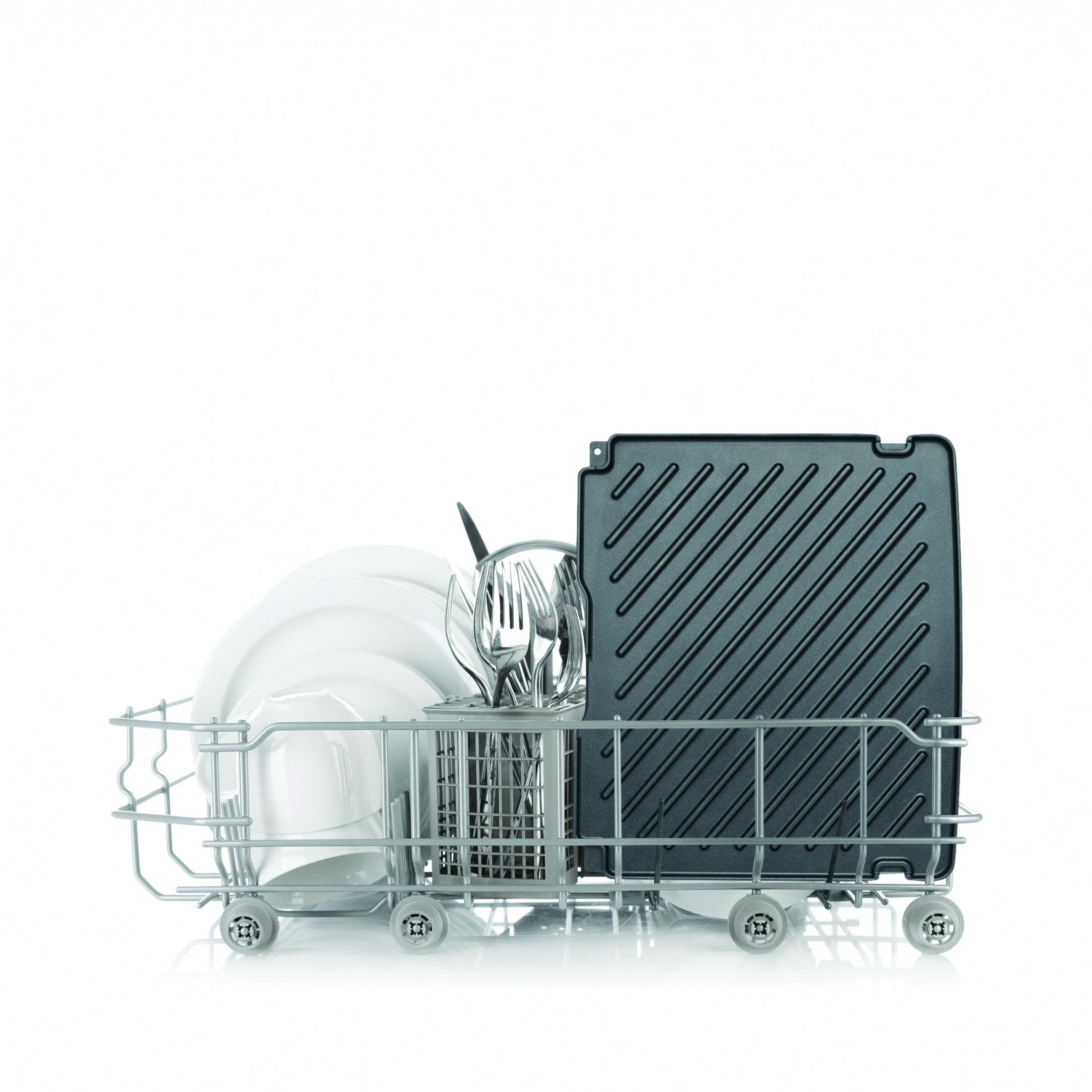 Koszyk zmywarki z talerzami, sztućcami i czarną patelnią grillową, na białym tle.