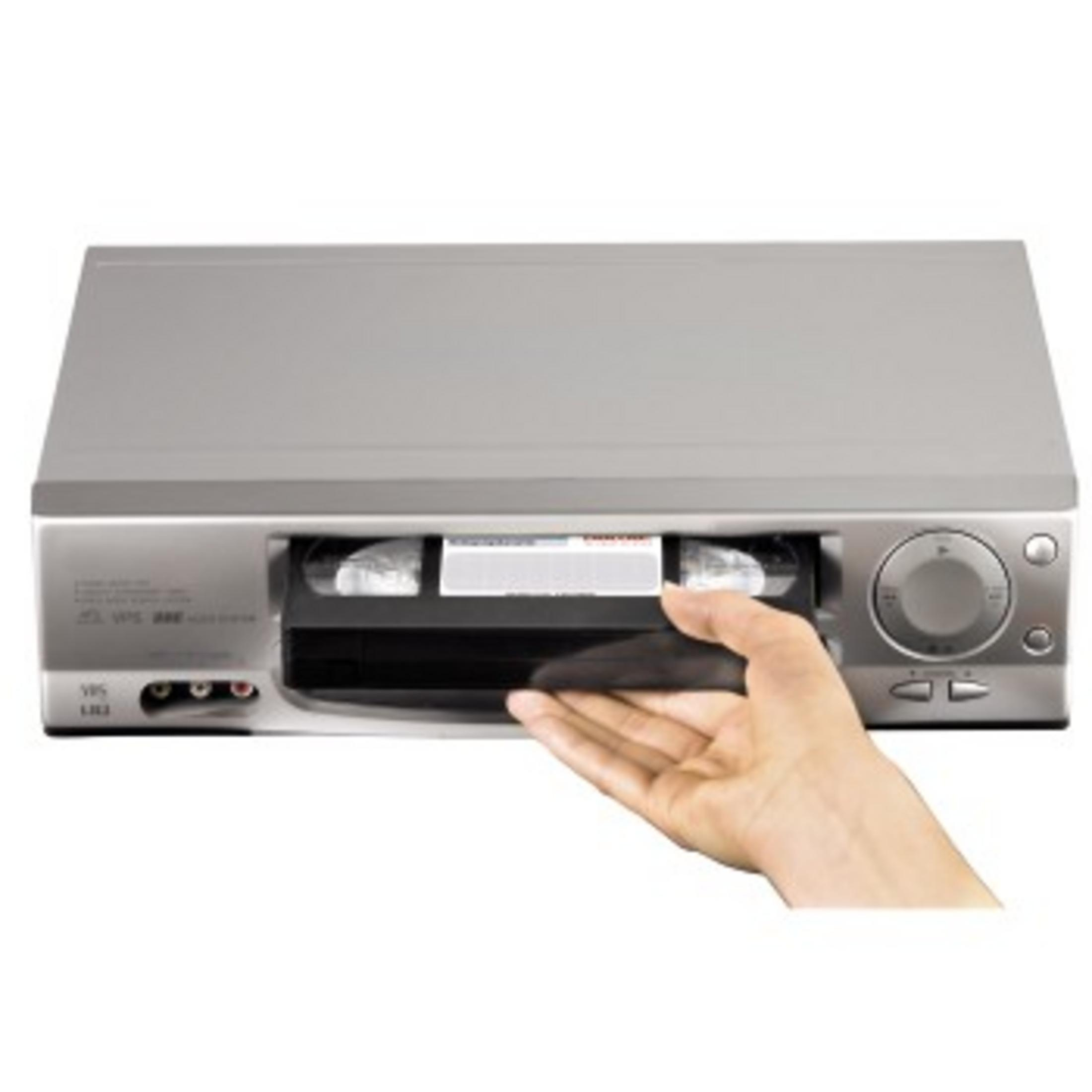 Eine Person legt eine VHS-Kassette in einen silbernen Videorekorder ein.