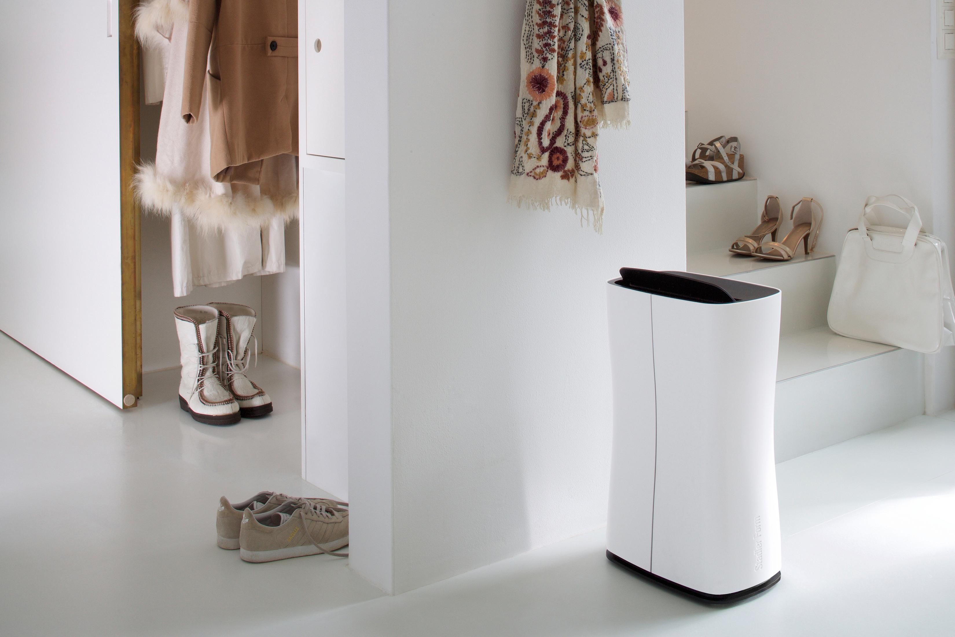 Een interieur met een witte luchtreiniger, schoenen en kleding.