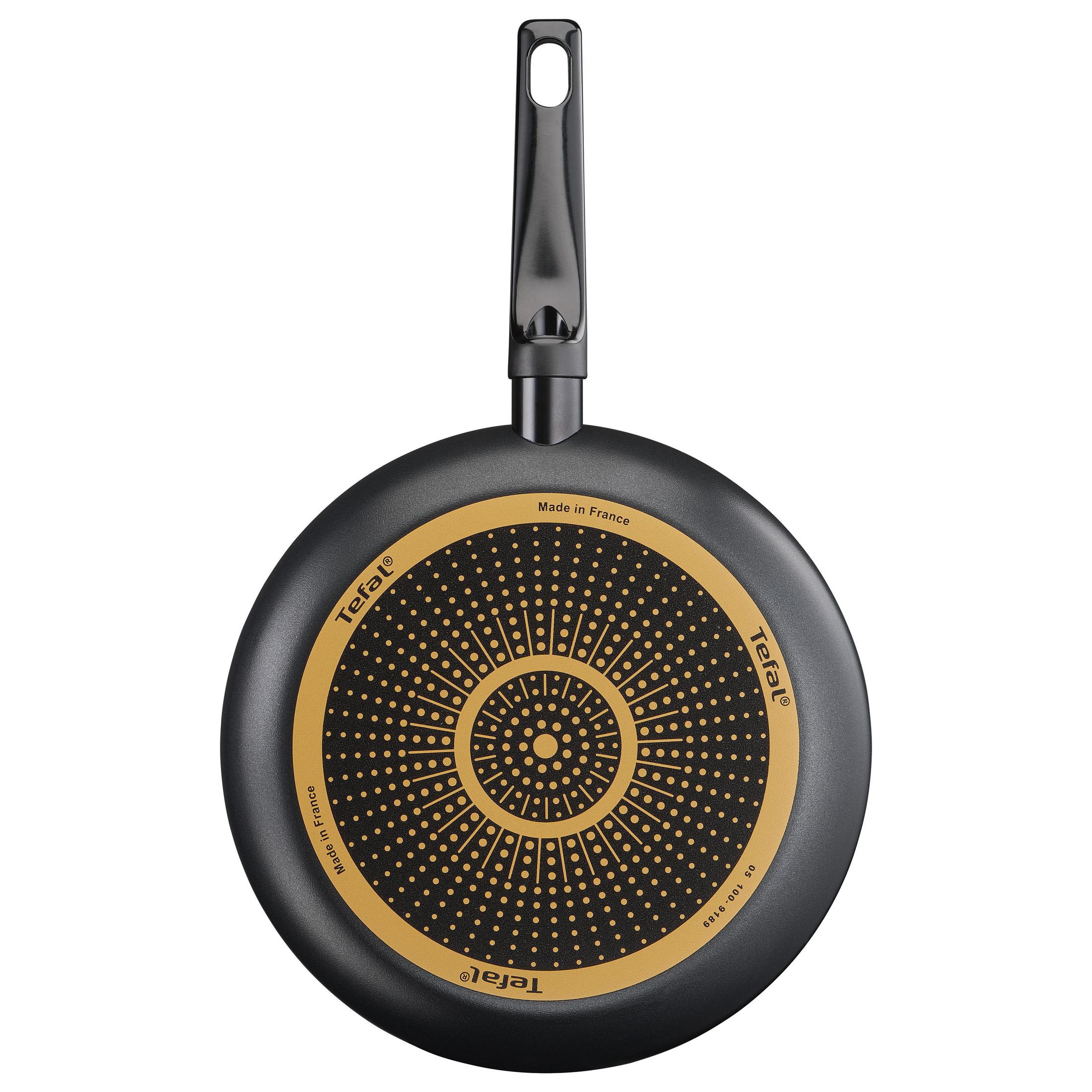 Le fond d'une poêle Tefal avec une surface antiadhésive, motif doré.