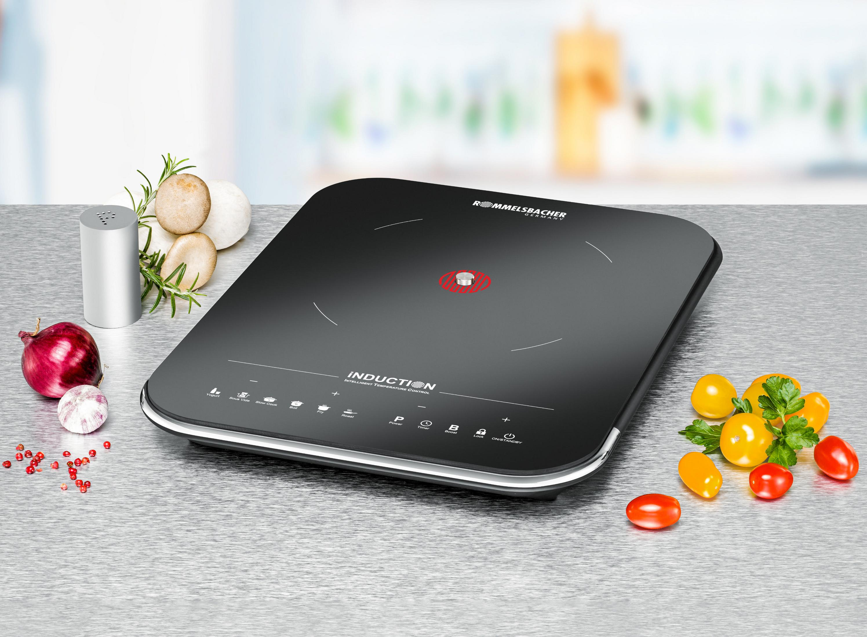 Płyta indukcyjna z warzywami, solą i przyprawami. Płyta jest czarna.