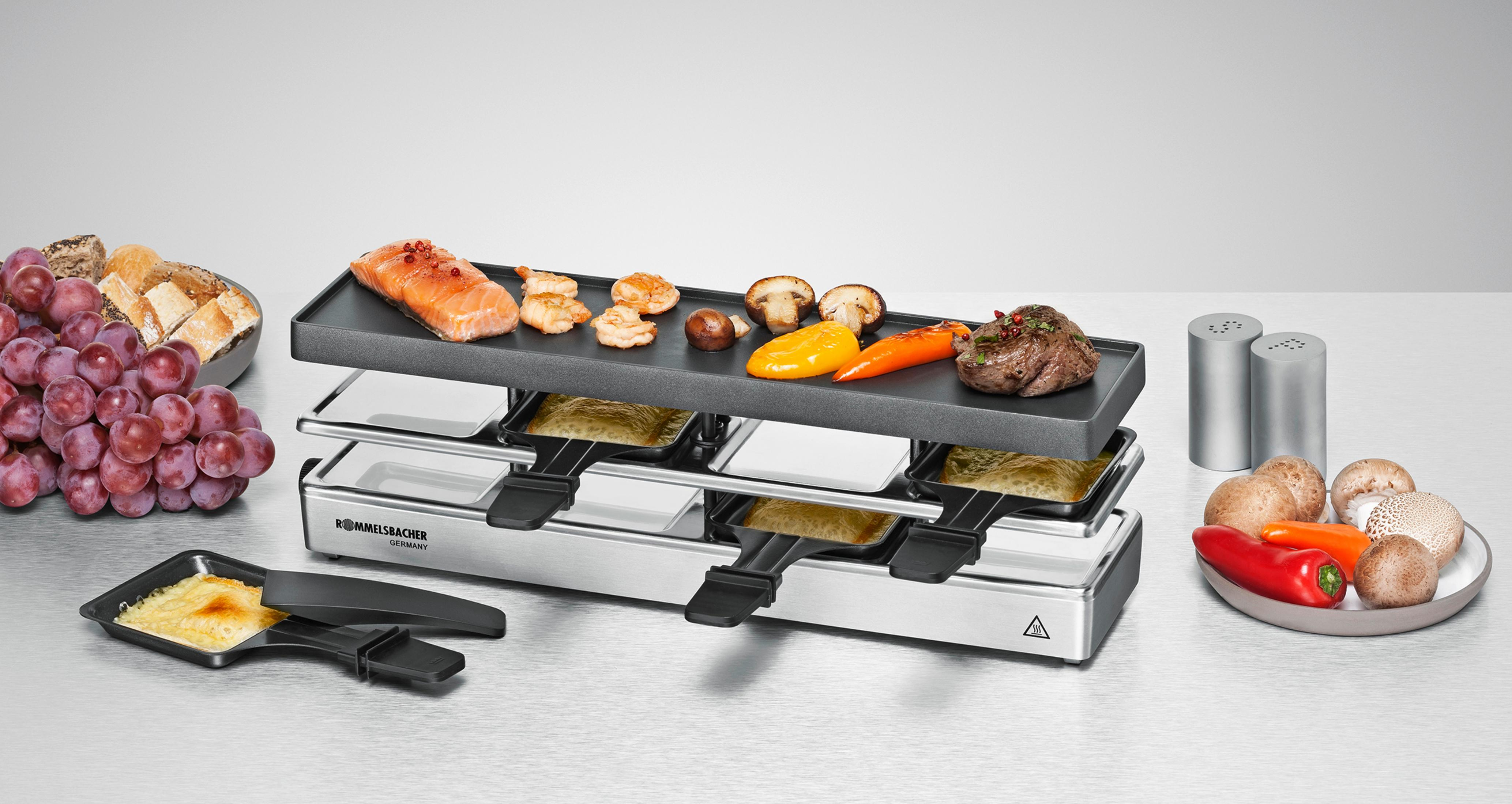 Grill do raclette z jedzeniem, w tym mięsem, warzywami i serem, na stole.