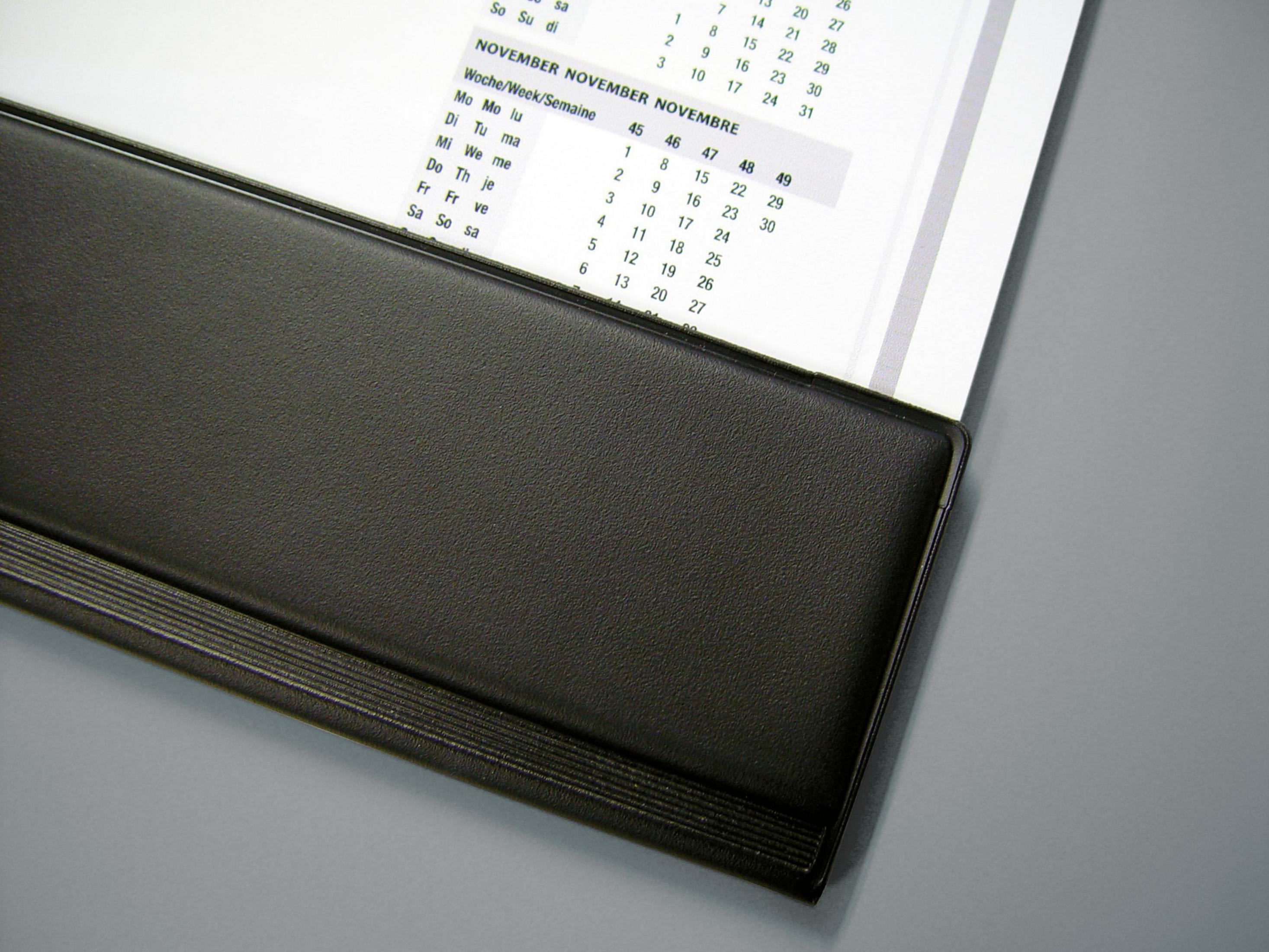 Ein Kalender, auf November geöffnet, mit schwarzem Sockel und grauem Hintergrund.