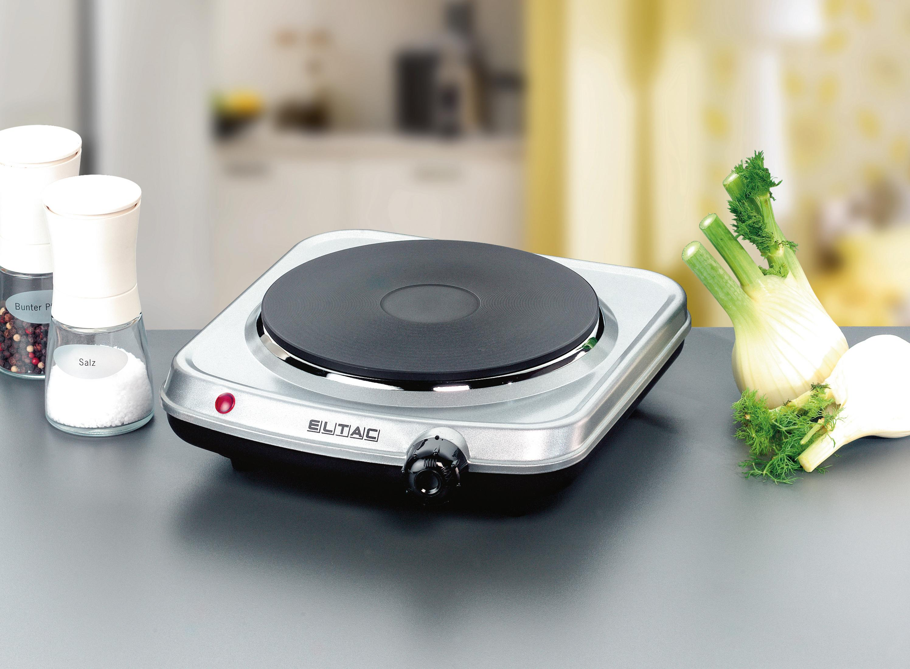 Elektrische Kochplatte mit Salz-, Pfefferstreuer und Fenchel auf Küchentheke.