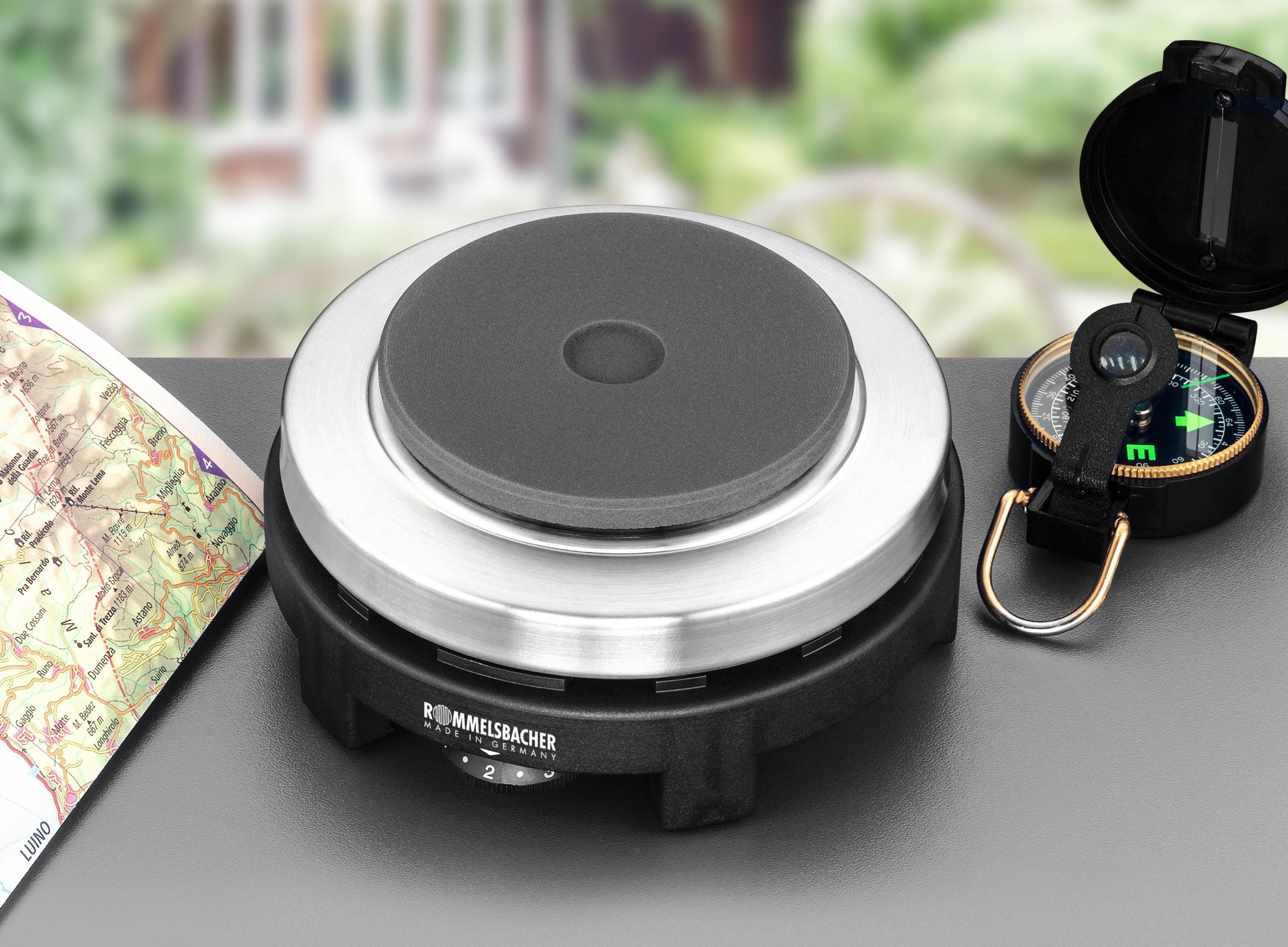 Un fornello portatile con bussola e mappa. Il fornello è nero e argento. Lo sfondo è sfocato.
