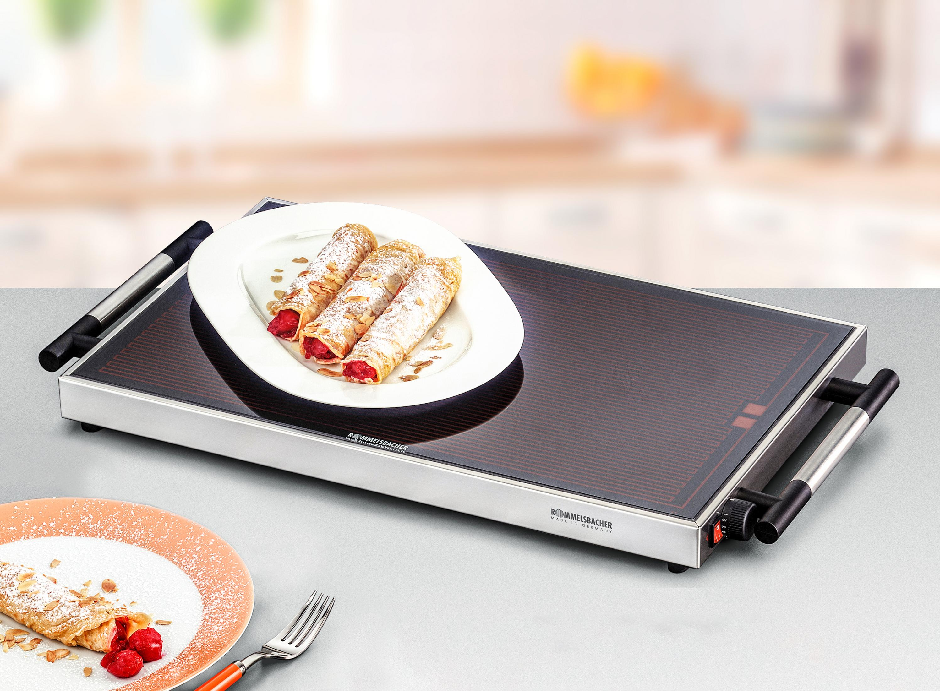 Ein Speisenwärmer mit Crêpes mit Früchten auf einem Tisch.