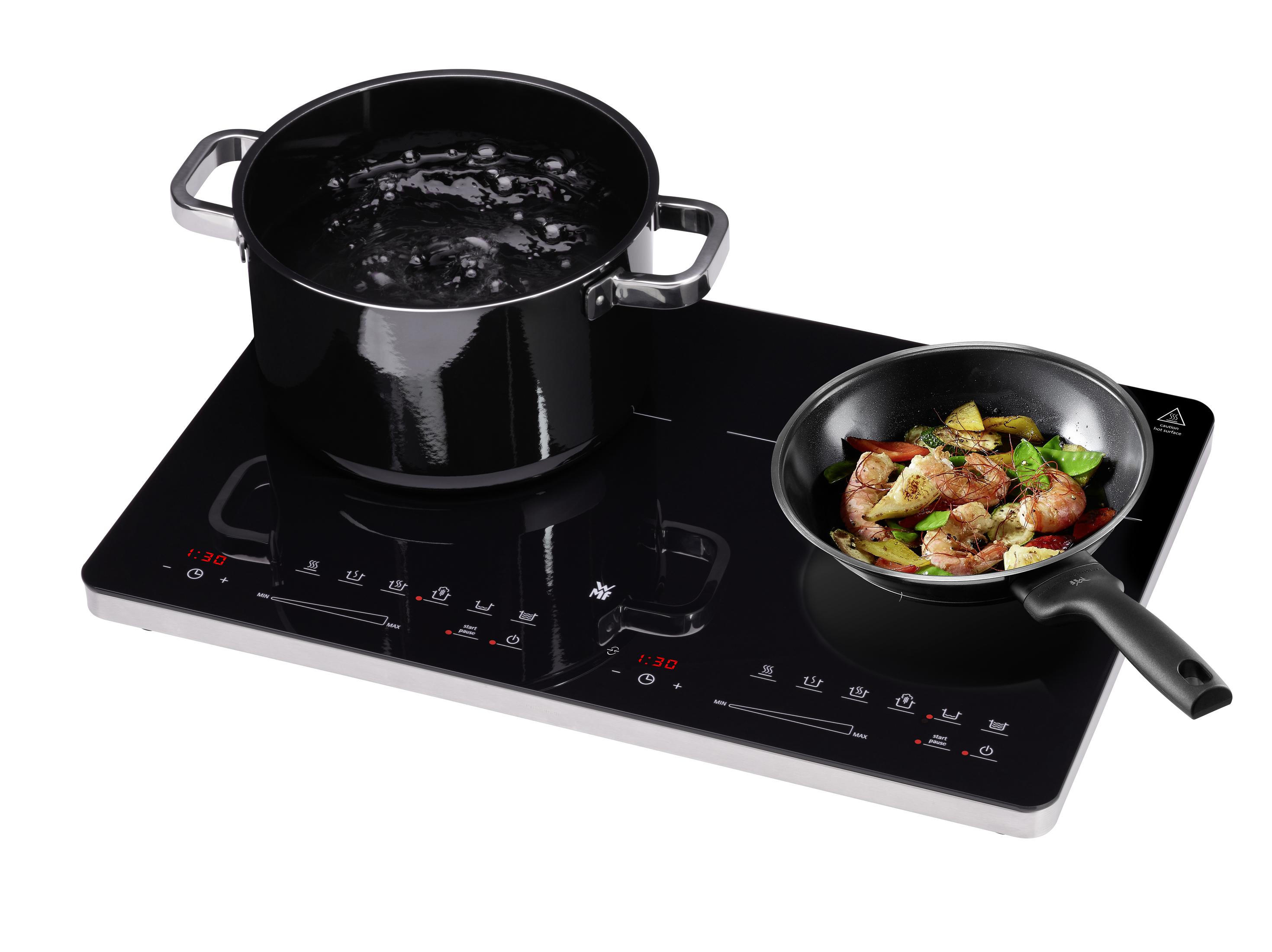 Schwarzes Induktionskochfeld mit Töpfen und Pfannen; Essen in einer Pfanne kochen.