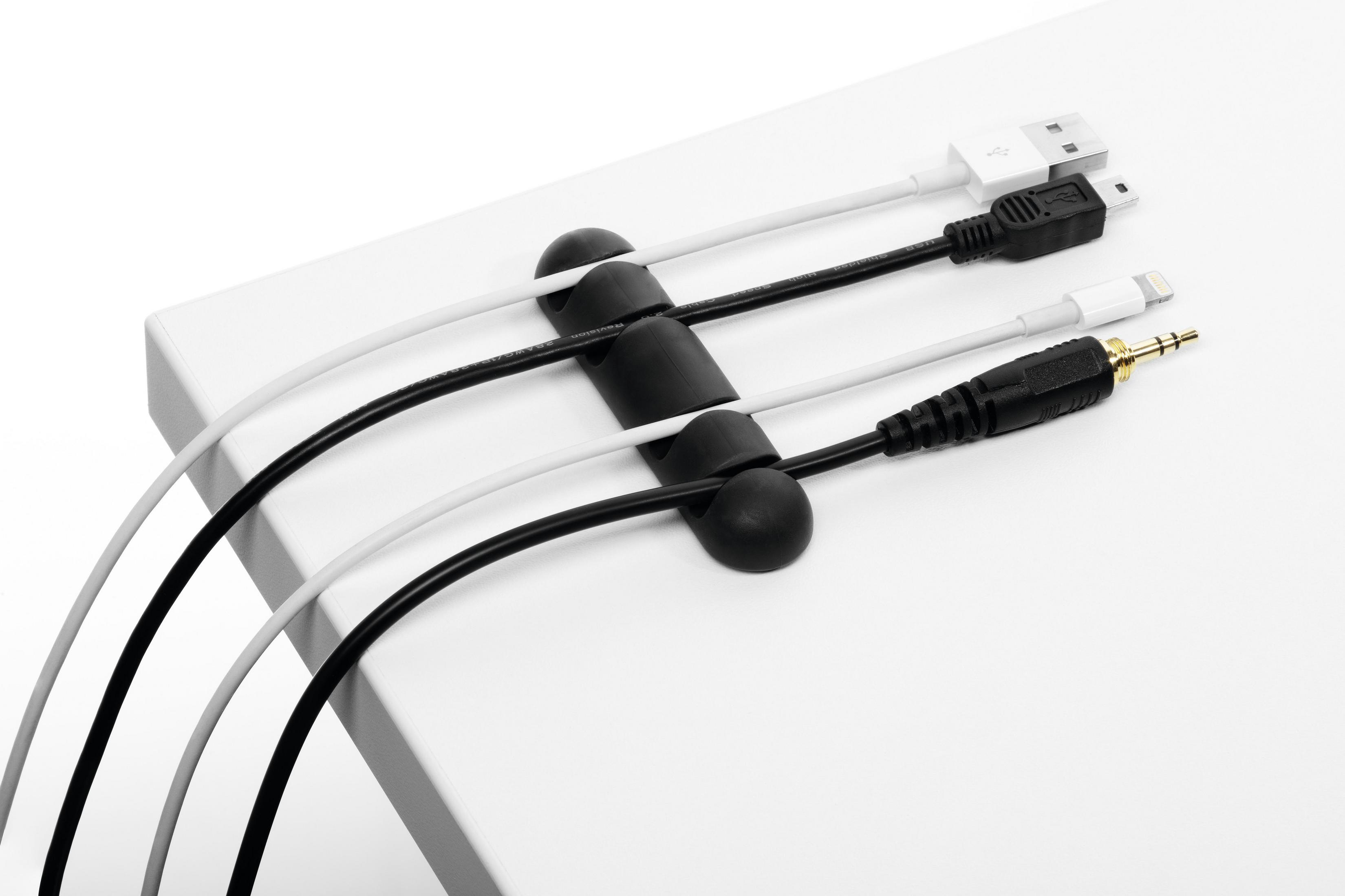 Weiße Kabel werden von einem schwarzen Kabel-Organizer auf weißer Oberfläche gehalten.