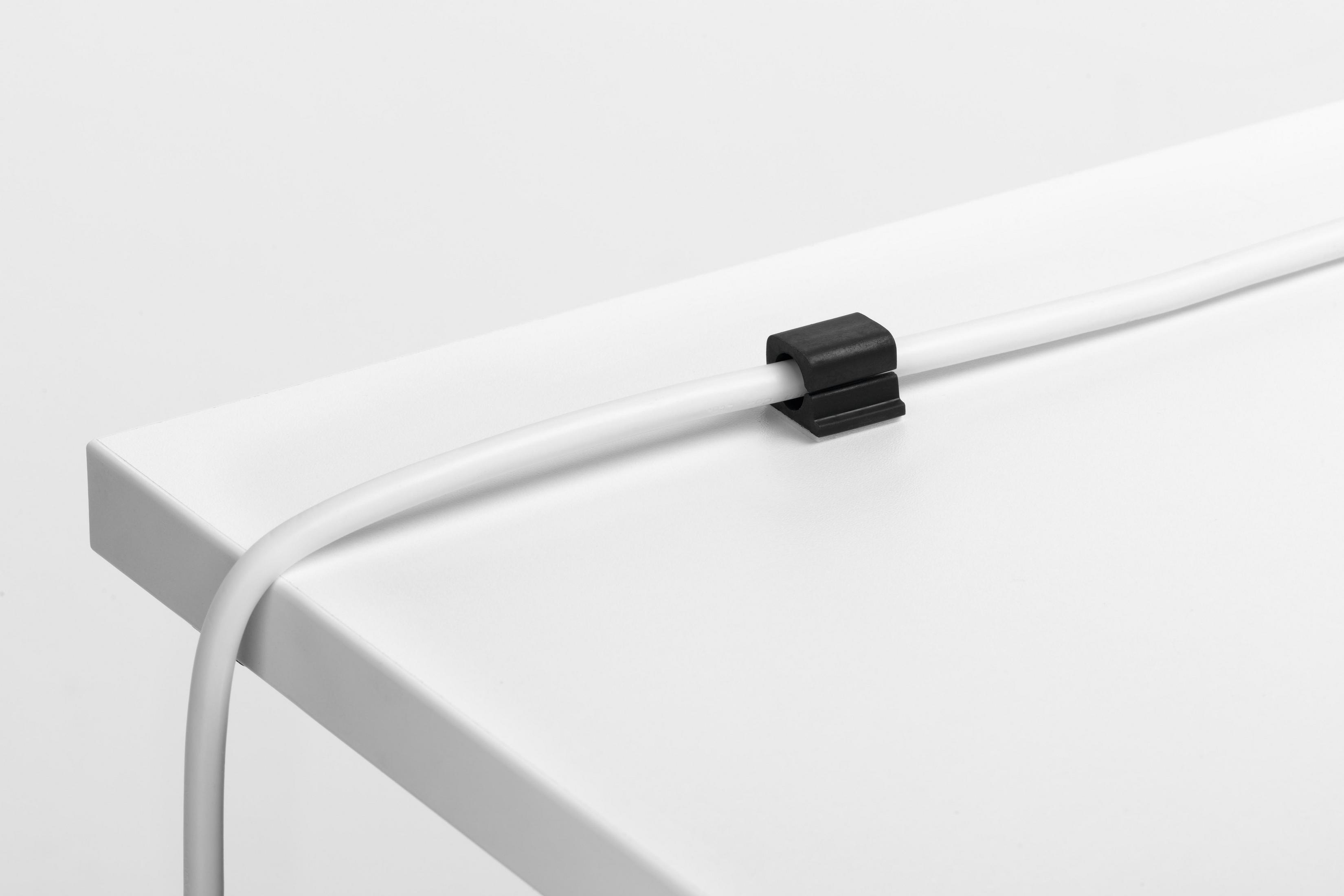 Ein weißes Kabel wird in einer schwarzen Kabelklemme auf einer weißen Oberfläche gehalten.
