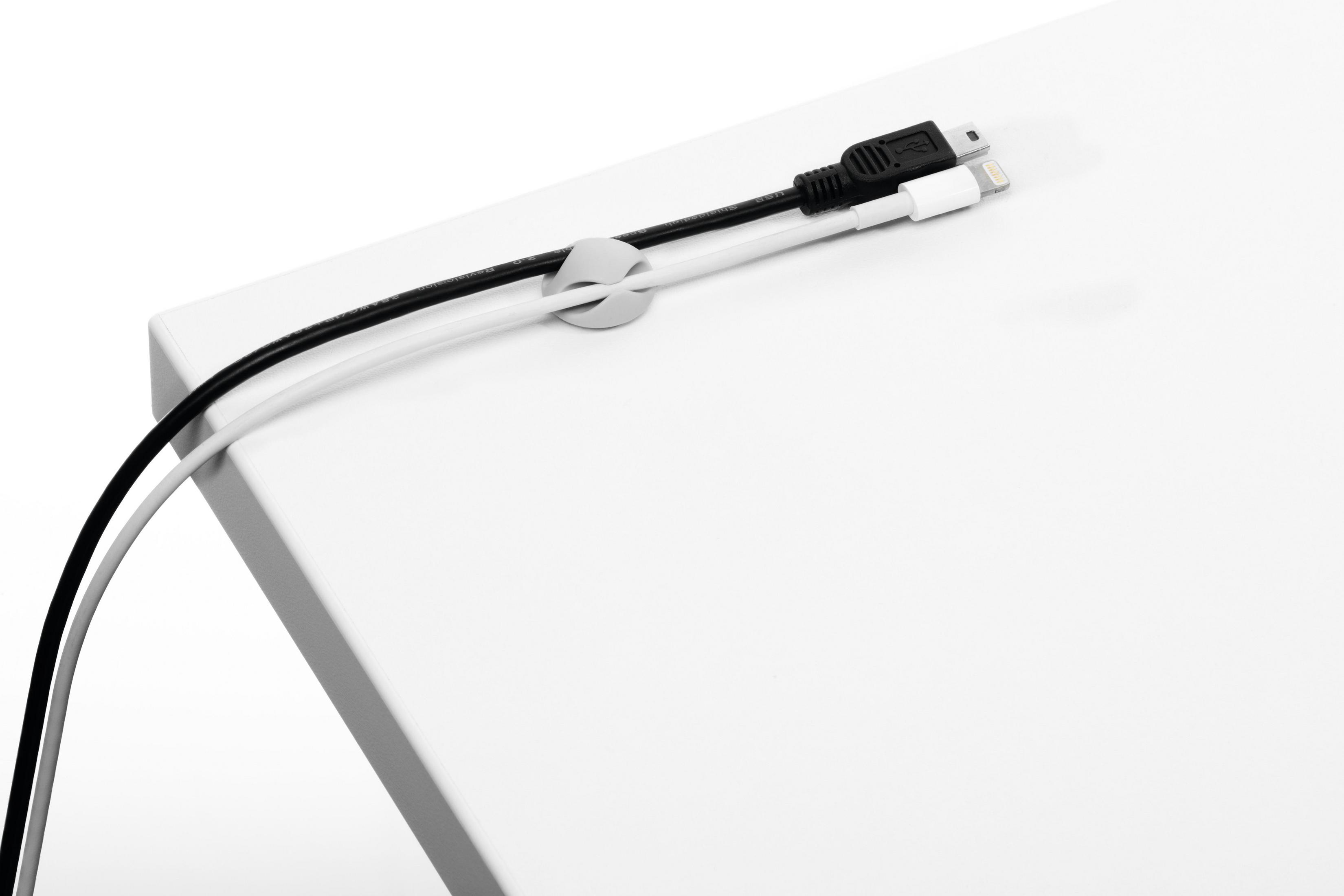 Zwei Ladekabel, die von einem Kabelorganisator auf einer weißen Oberfläche gehalten werden.