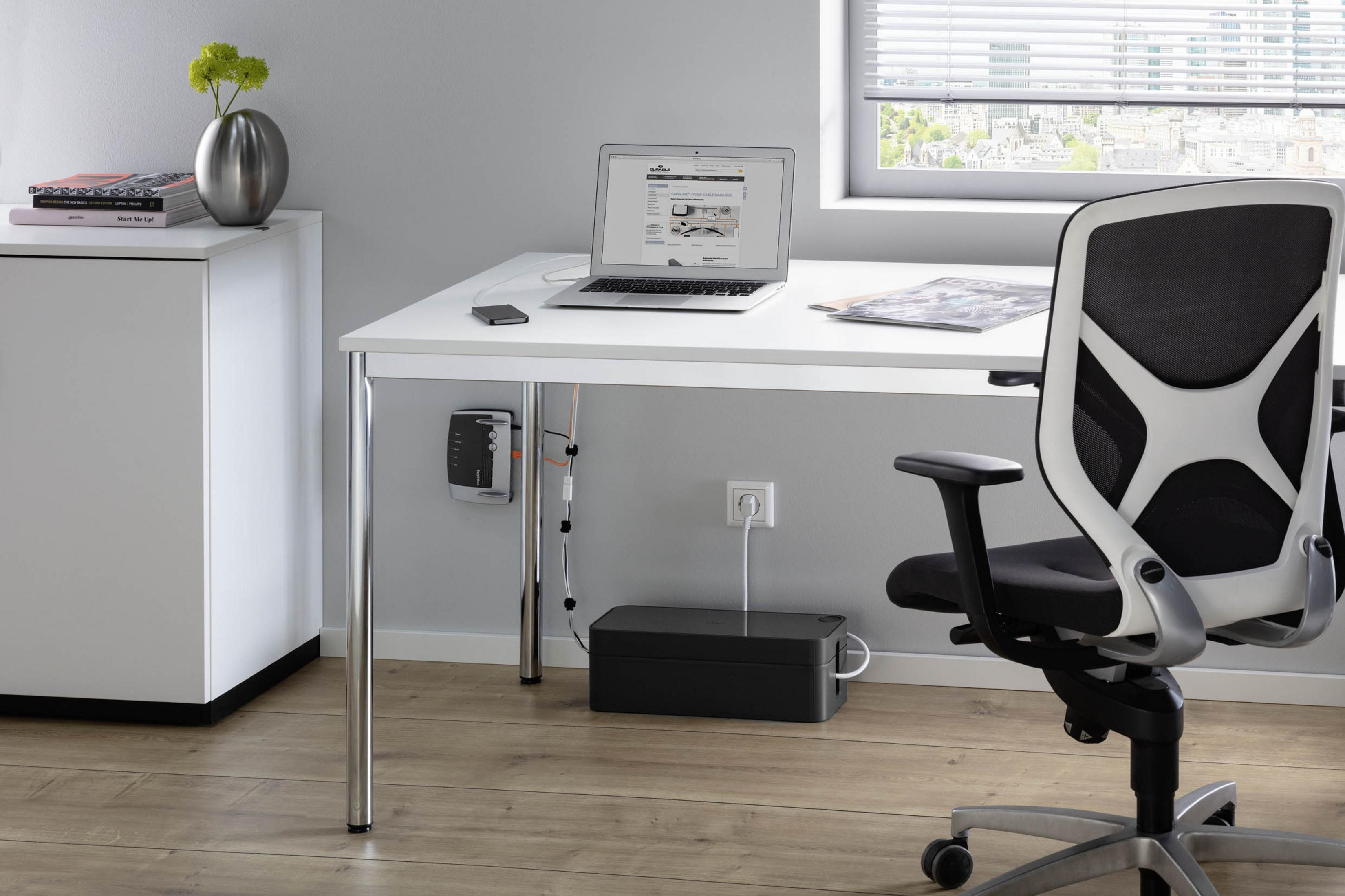 Bürotisch mit Laptop, Telefon, Stuhl und Kabeln, mit einem Fenster im Hintergrund.