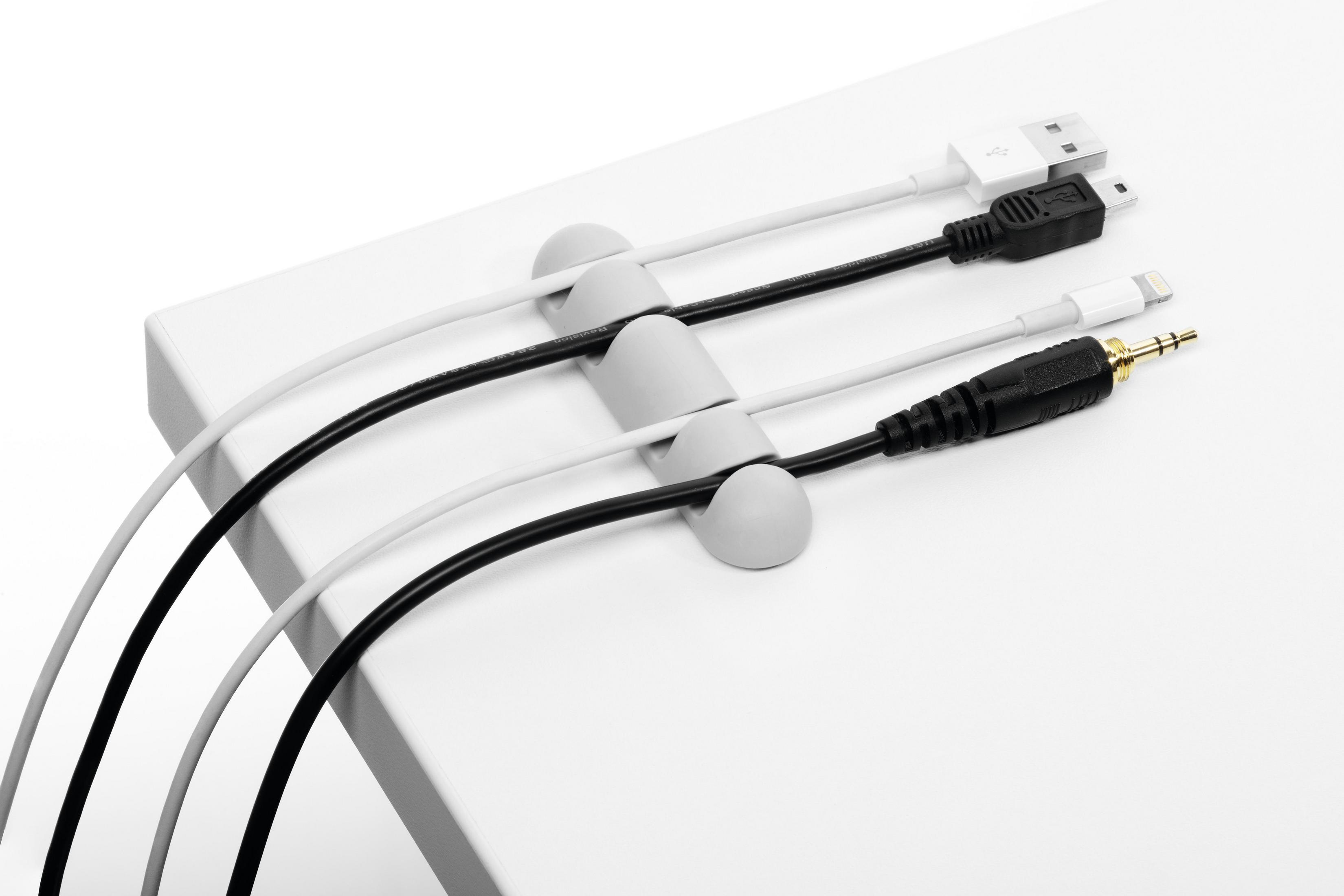 Weißer Schreibtisch mit Kabelhaltern. Vier Kabel unterschiedlicher Typen werden gehalten.