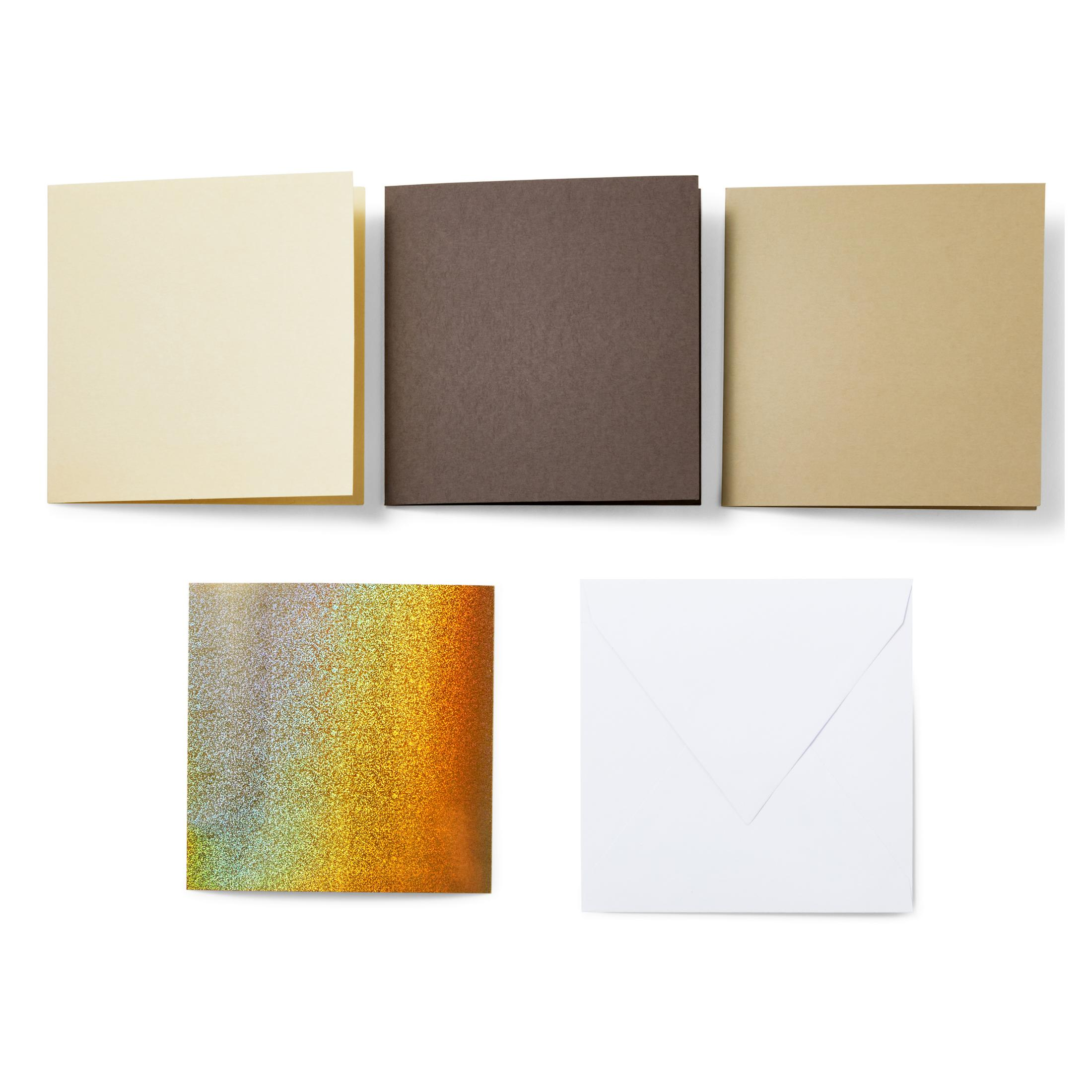 Drei quadratische Karten und zwei Umschläge auf Weiß. Karten sind beige, braun und beige. Eine hat Glitzer.