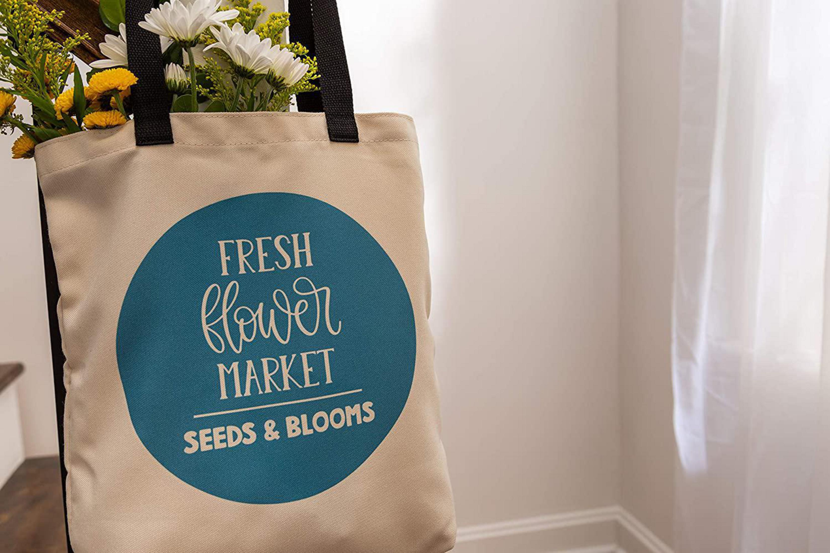 Tragetasche mit Blumen und den Worten 'FRESH flower MARKET SEEDS & BLOOMS'.