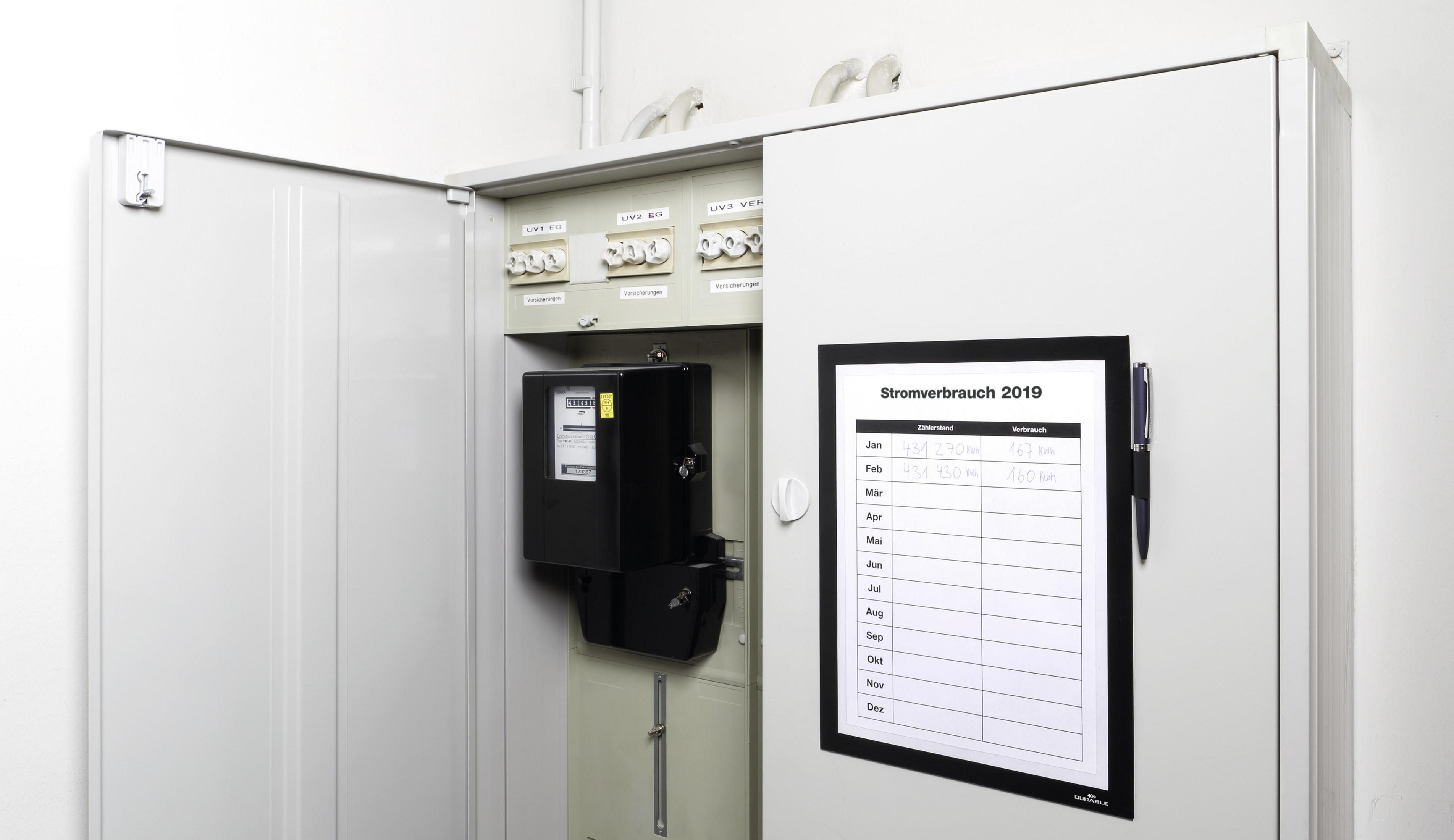 Offener Elektroschrank mit Stromzähler und Papier mit Stromverbrauchsdetails.