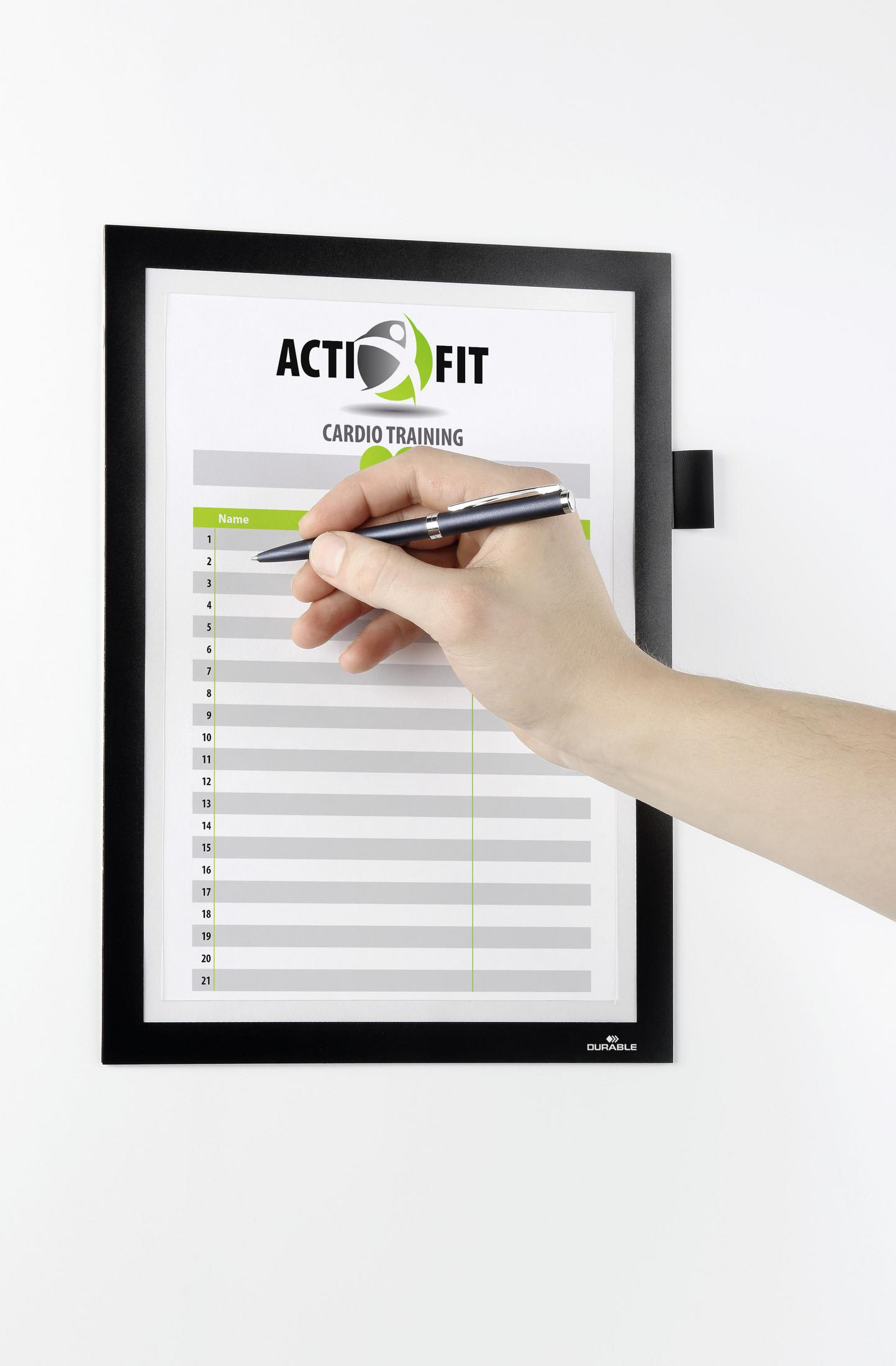 Eine Hand, die auf einer Cardio-Trainingskarte auf einer schwarz gerahmten Tafel schreibt.