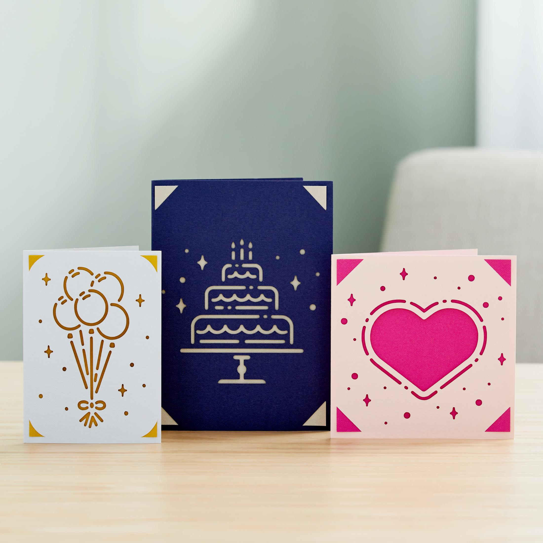 Drei Grußkarten mit Illustrationen. Eine weiße Karte mit Luftballons, eine blaue mit Kuchen.