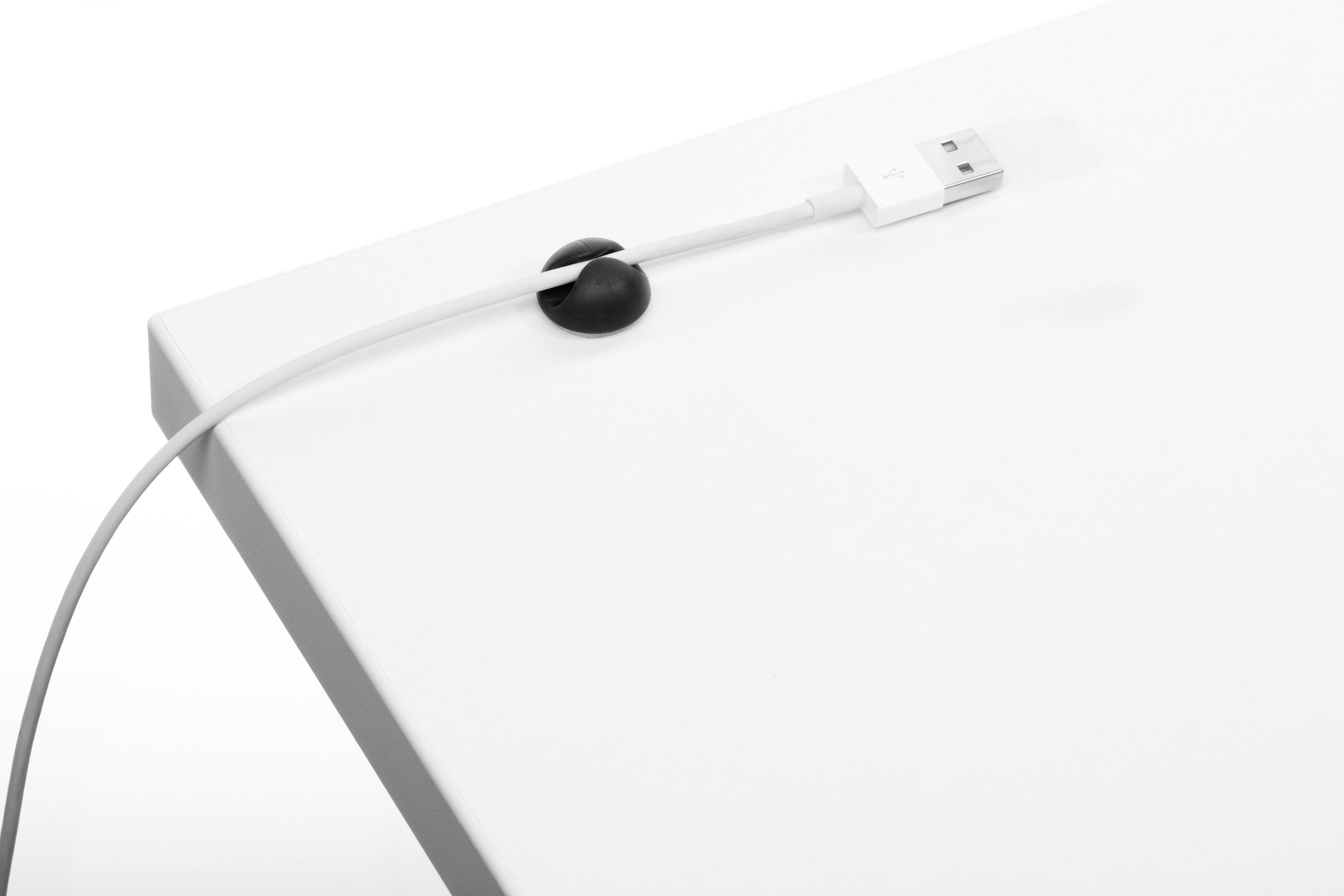 Ein weißer Schreibtisch mit einem schwarzen Kabelclip, der ein Ladekabel hält. Das Ende ist USB.