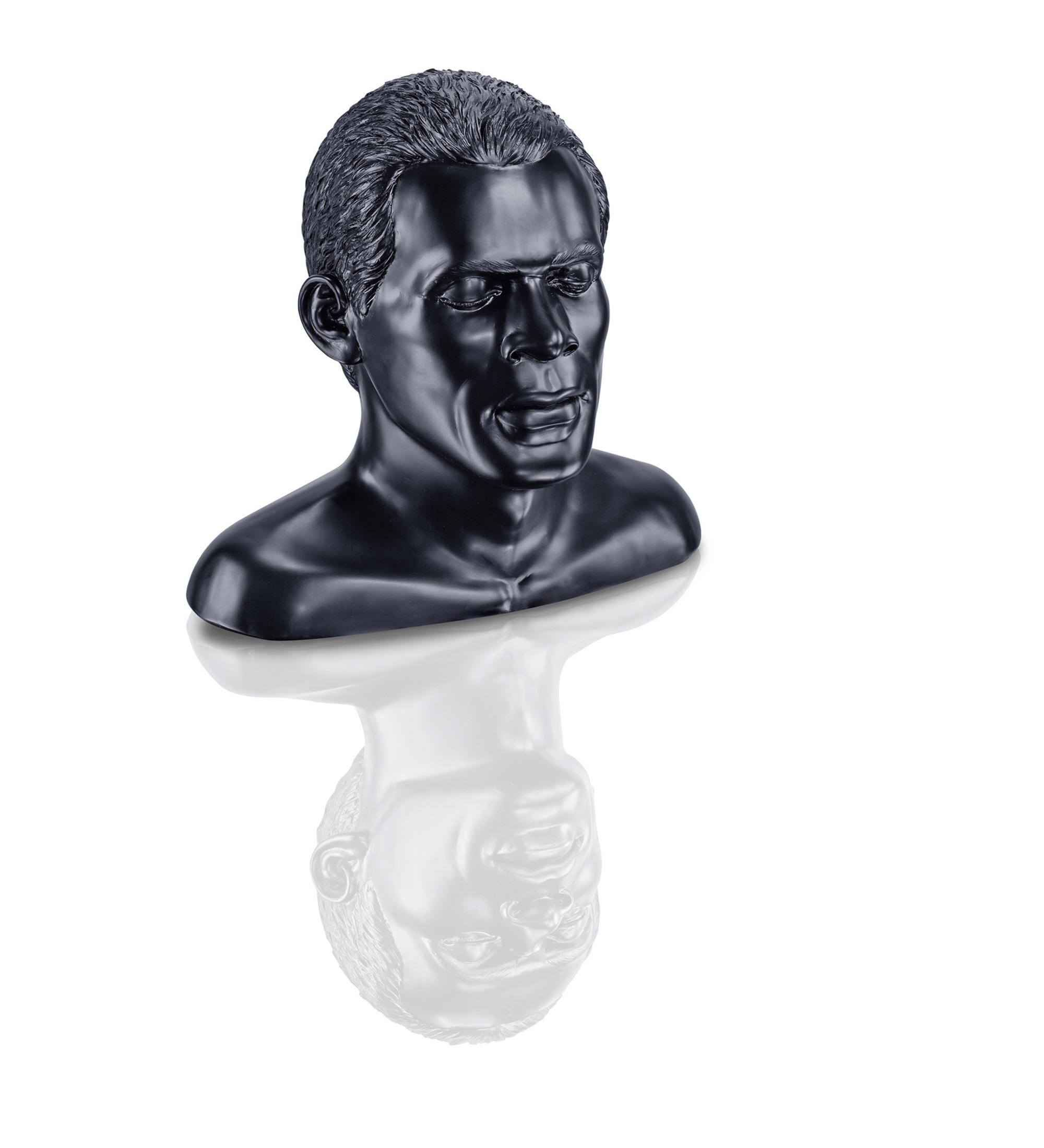 Schwarze Büstenskulptur eines Mannes mit leicht geneigtem Kopf. Die Büste spiegelt sich.