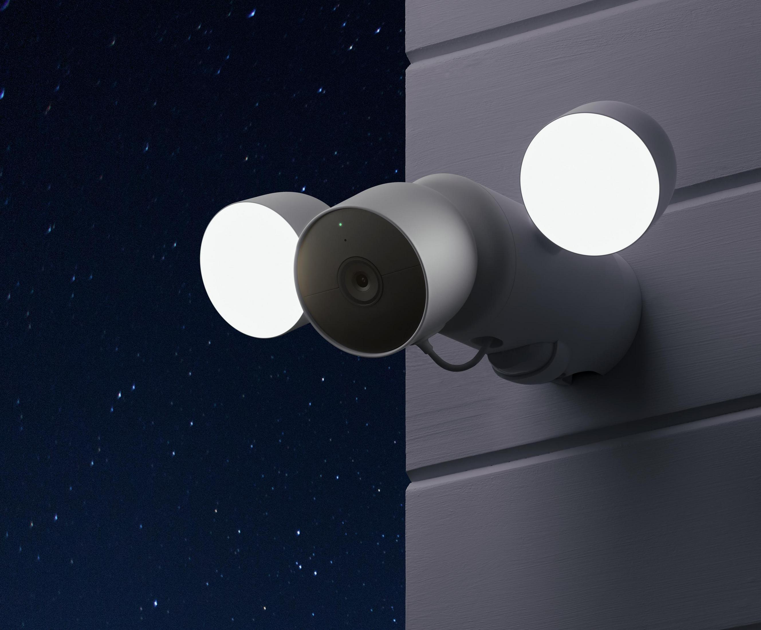 Nocny obraz kamery bezpieczeństwa z dwoma światłami. Niebo jest ciemne i pełne gwiazd. Kamera znajduje się na białej ścianie.
