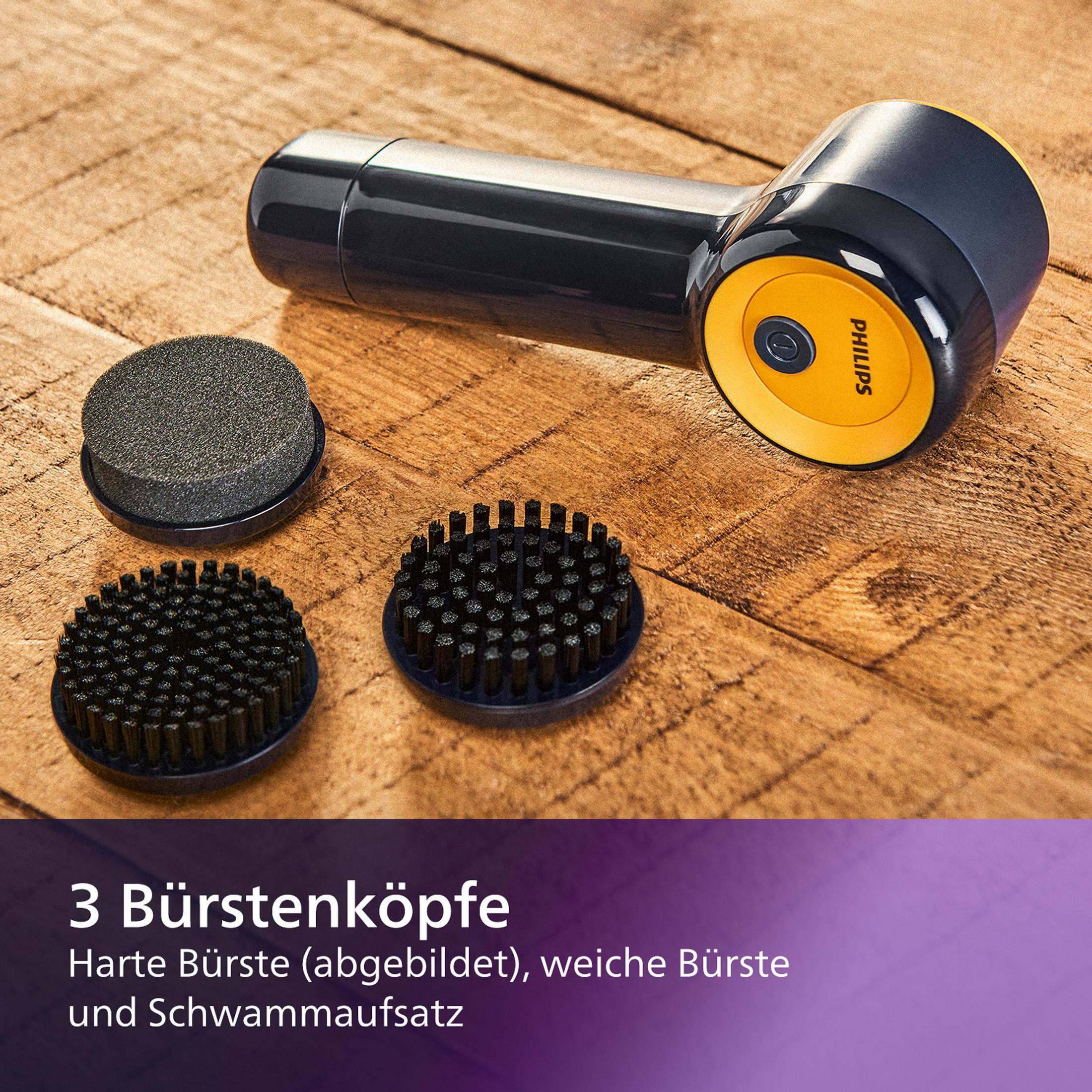 Ein schwarzer und gelber Philips-Schuhputzer mit drei Bürstenköpfen auf einer Holzoberfläche. Die Köpfe sind ein Schwamm und zwei Bürsten.