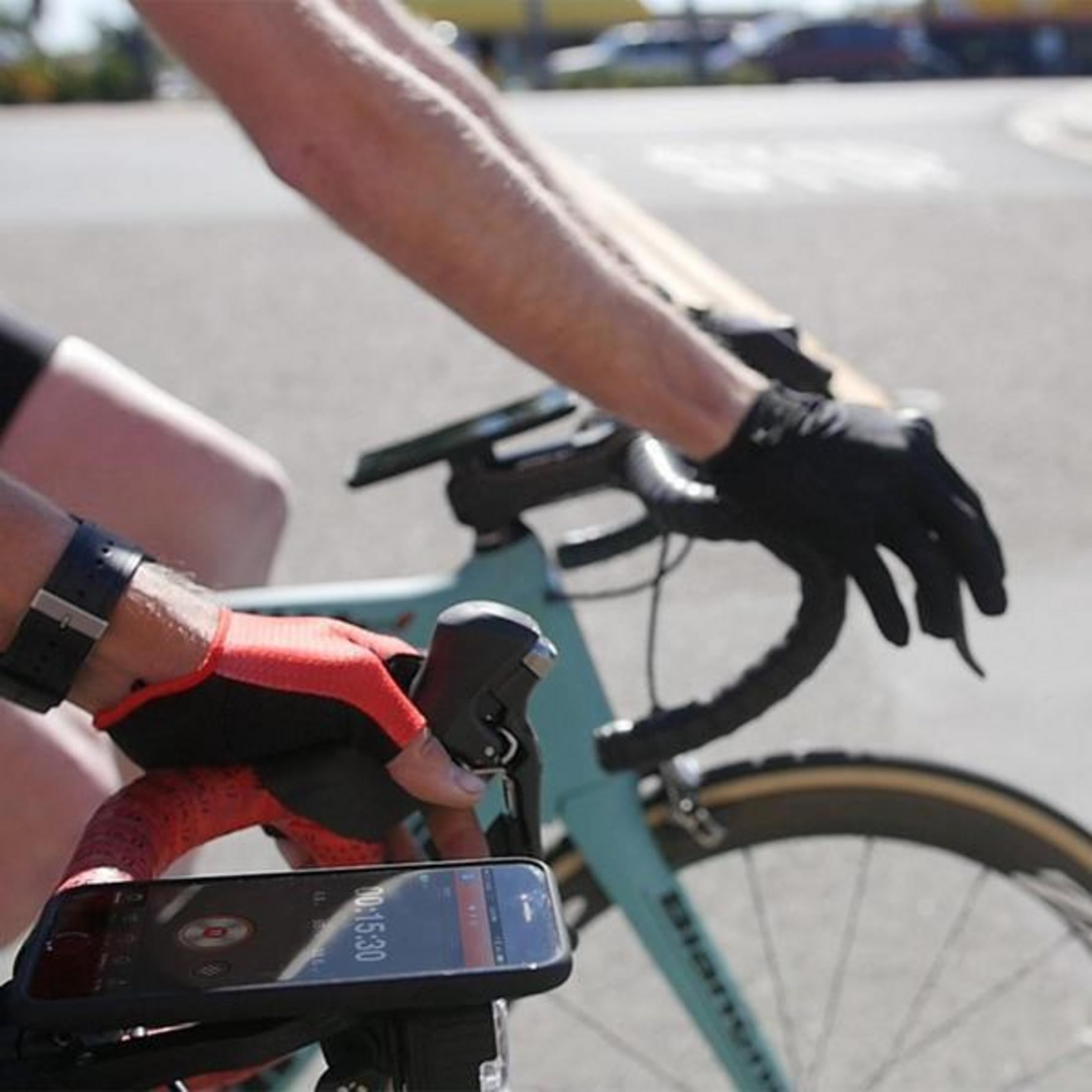 Radfahrer hält Telefon am Lenker. Anzeige zeigt Timer und Geschwindigkeit. Nahaufnahme.