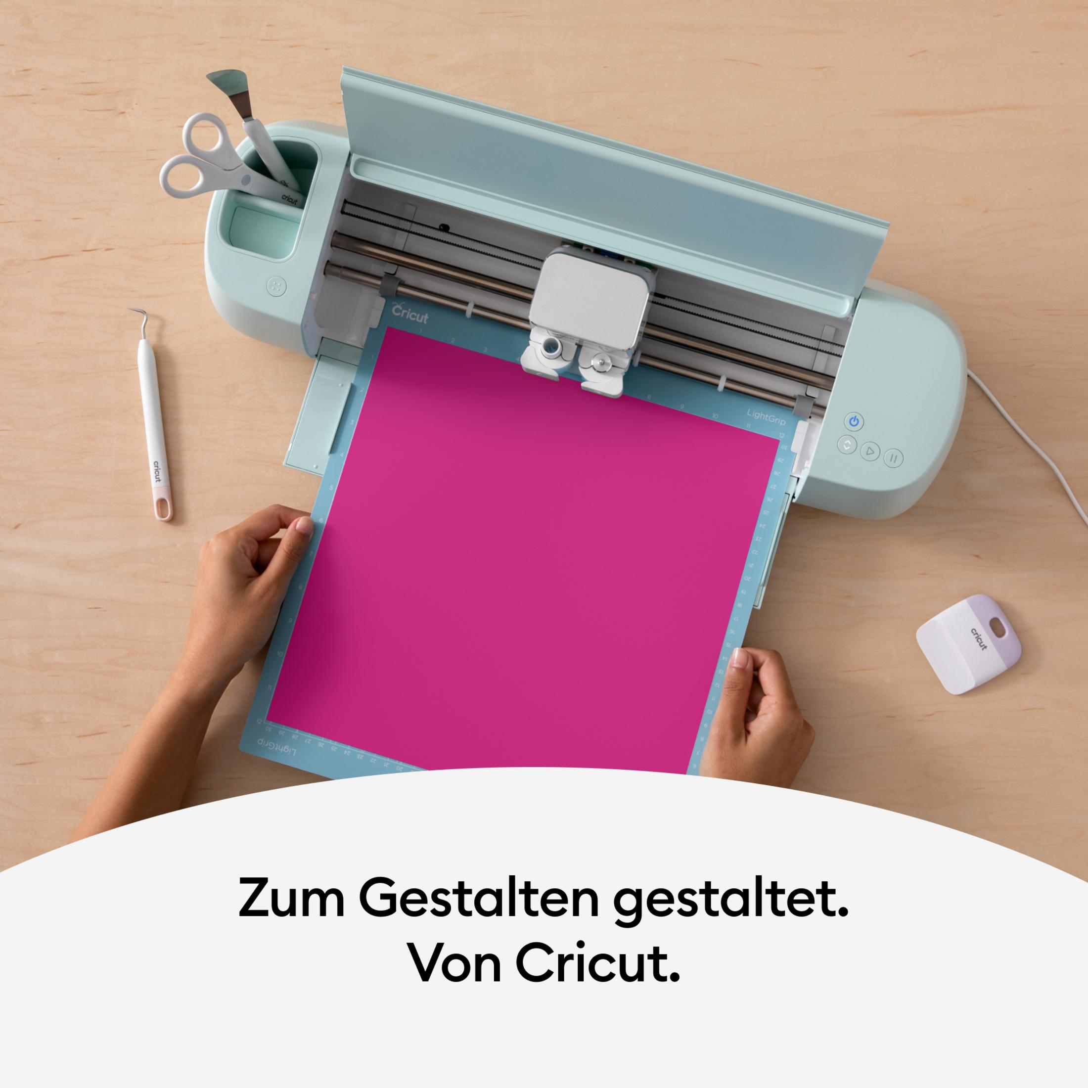 Person verwendet Cricut-Maschine mit rosa Papier. Holzoberfläche.