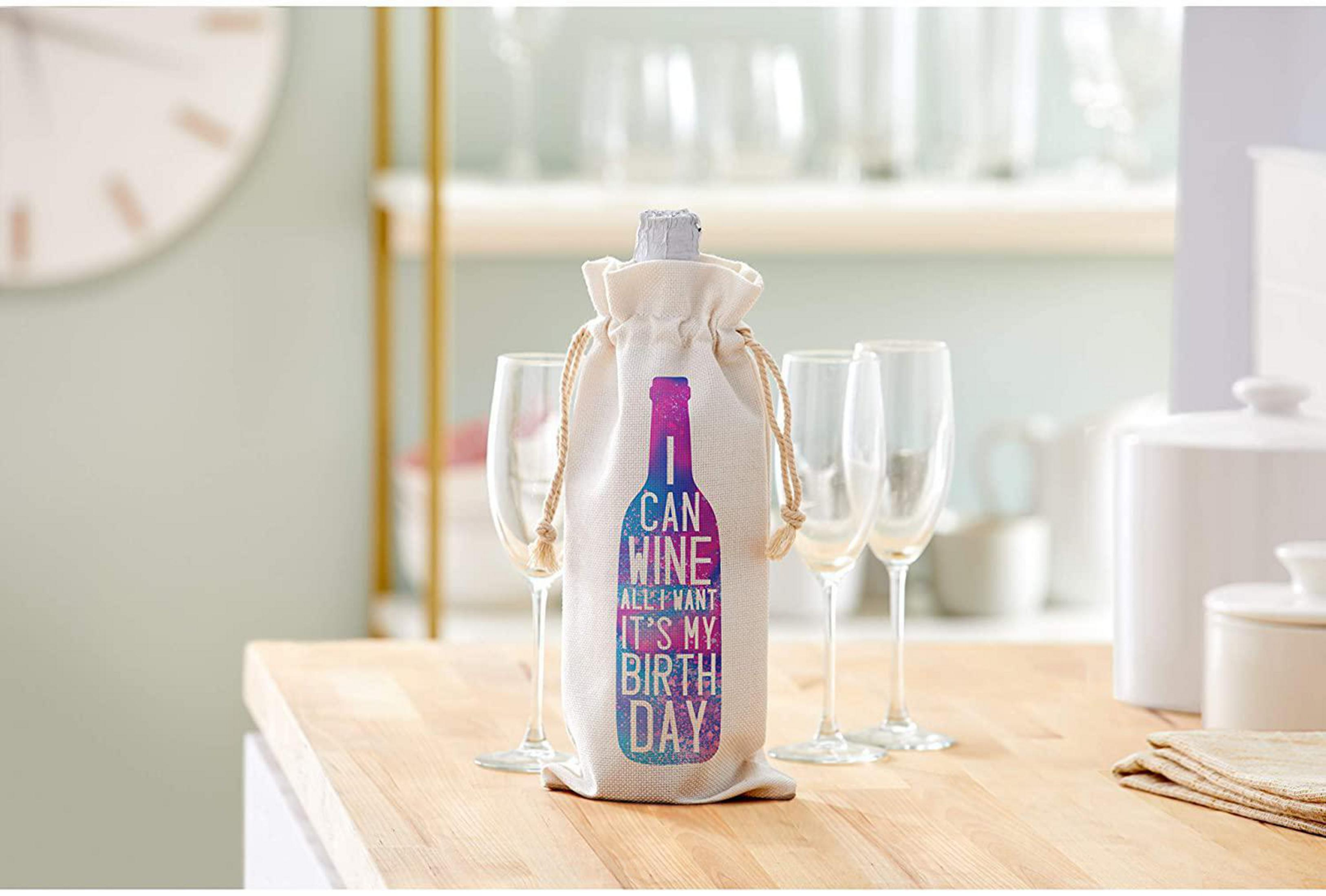 Weinflasche in einer Tasche mit Text: "CAN WINE ALL I WANT IT'S MY BIRTHDAY" und Gläser.