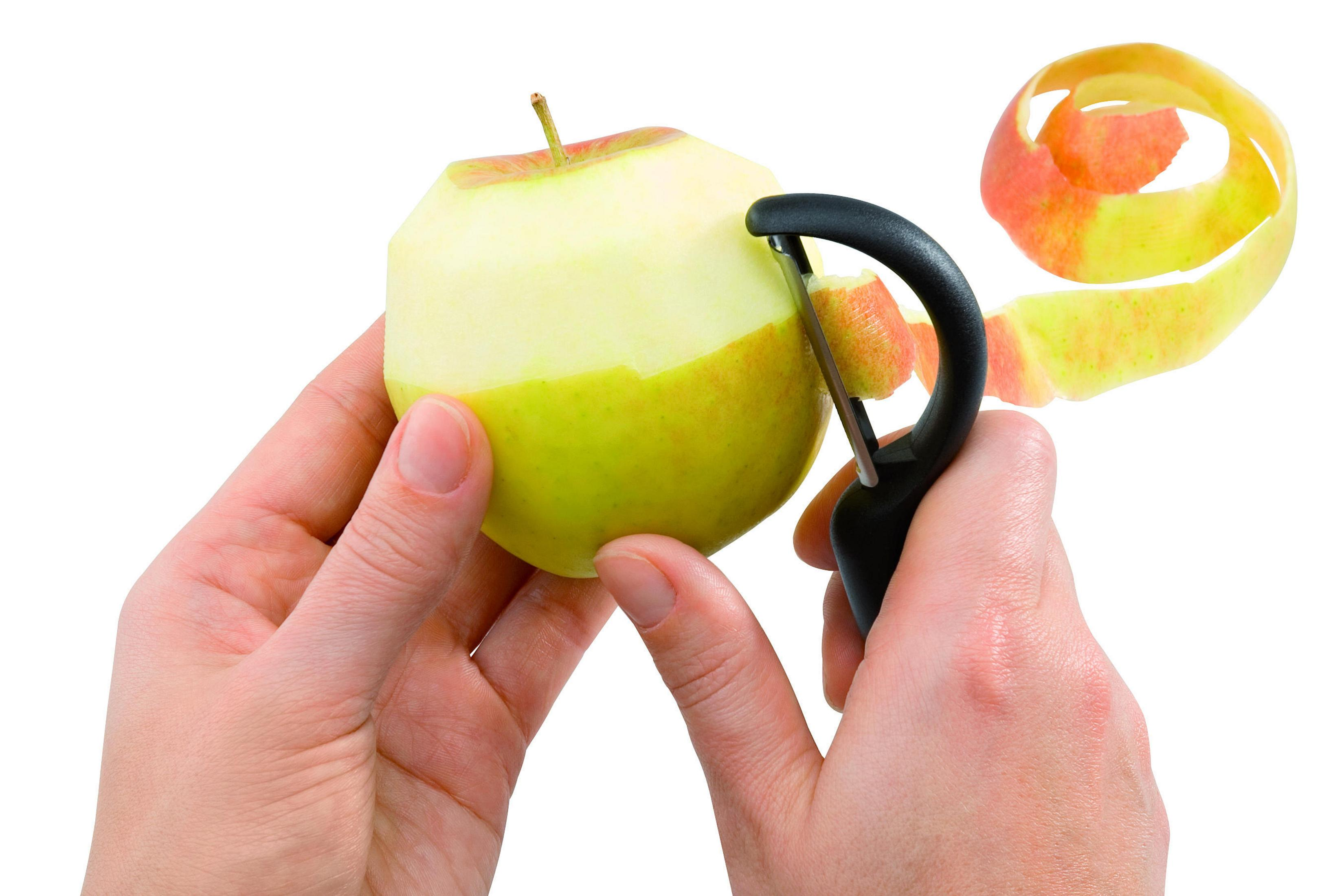 Hände schälen einen Apfel und entfernen die Schale mit einem schwarzen Schäler.