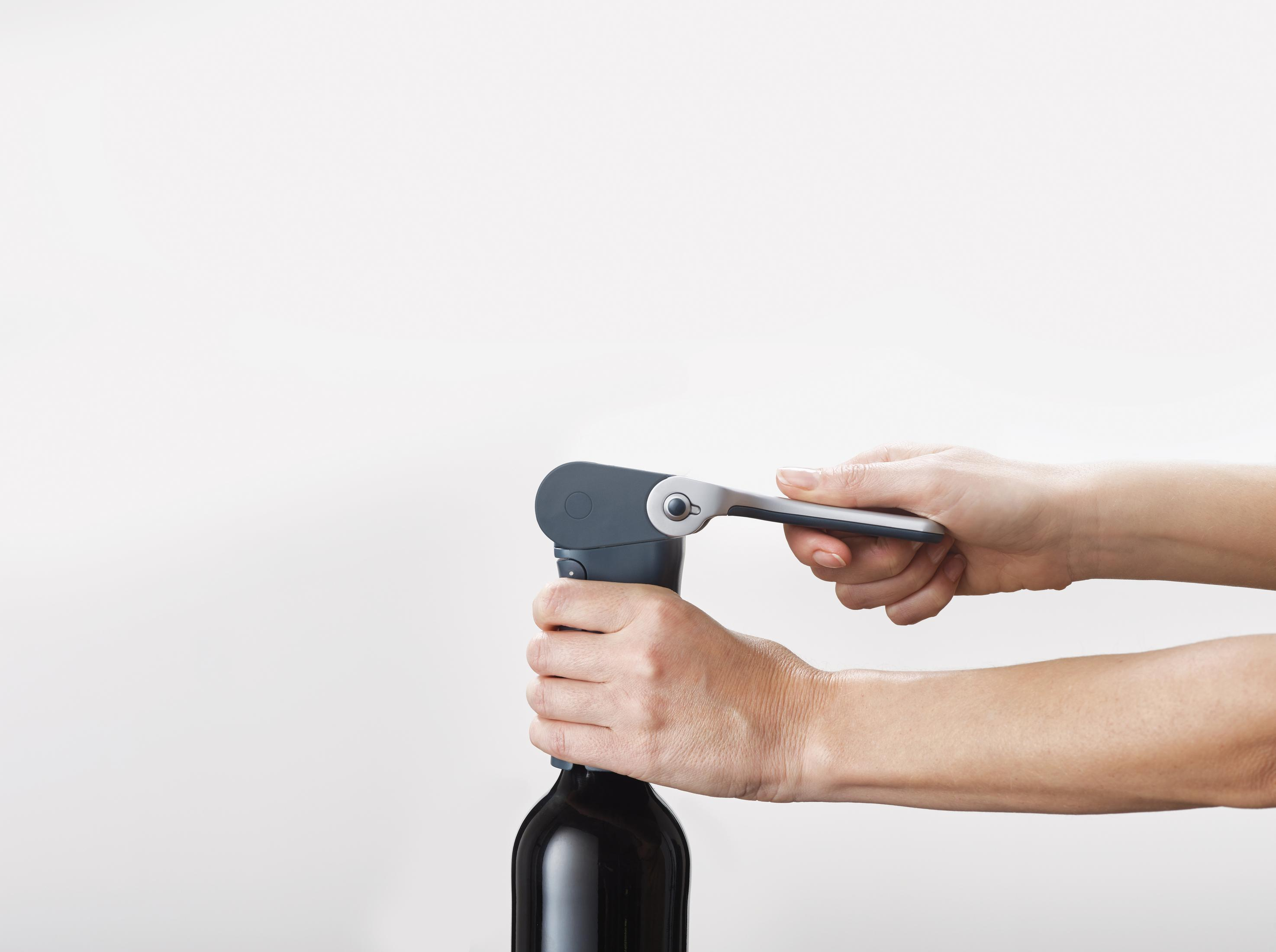 Hände benutzen einen Weinöffner an einer Weinflasche.