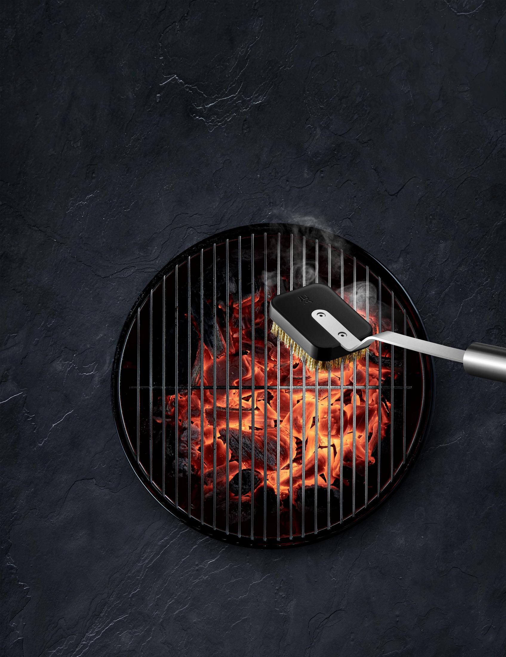 Grill mit heißen Kohlen, Bürste reinigt.