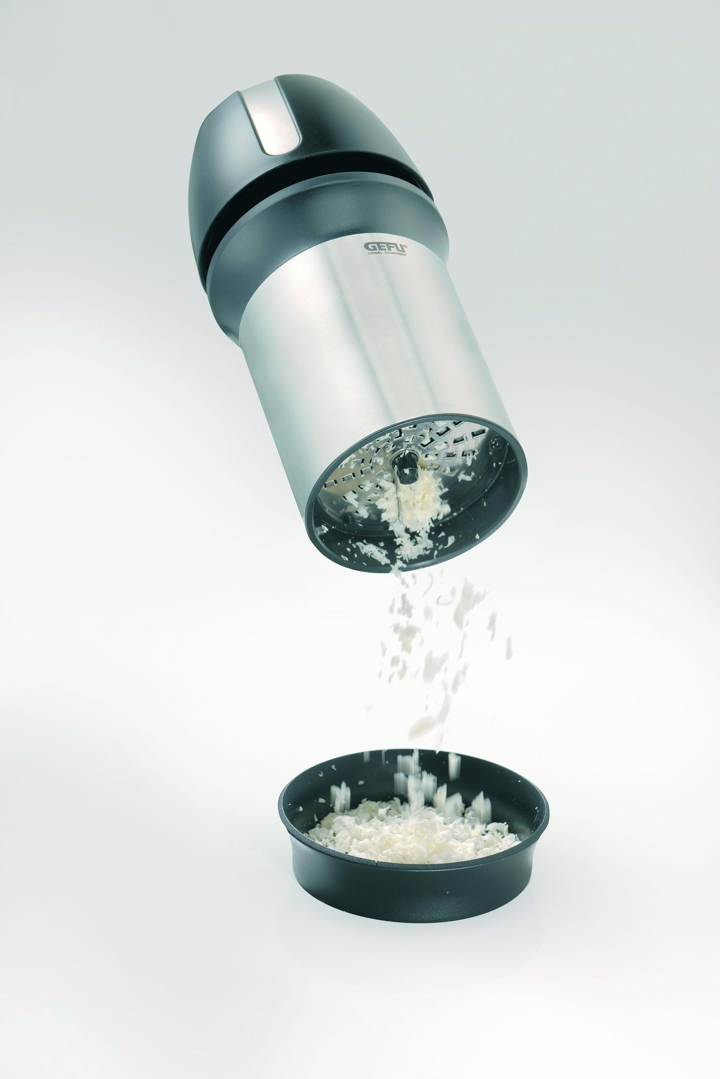 Tarka z startym serem wpadającym do miski. Białe tło.