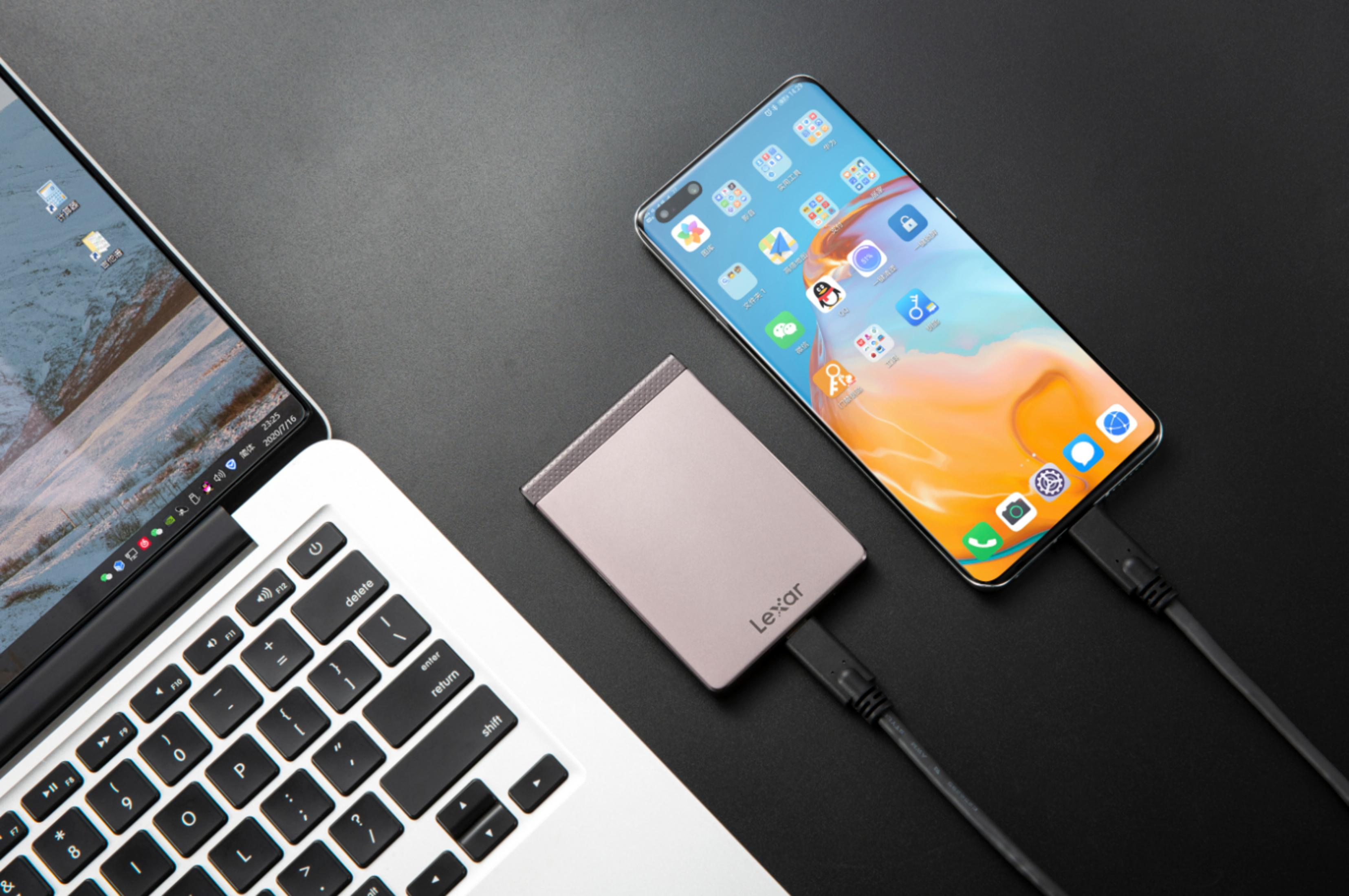 Laptop, telefon i zewnętrzny dysk twardy podłączone na czarnej powierzchni. Telefon wyświetla aplikacje.