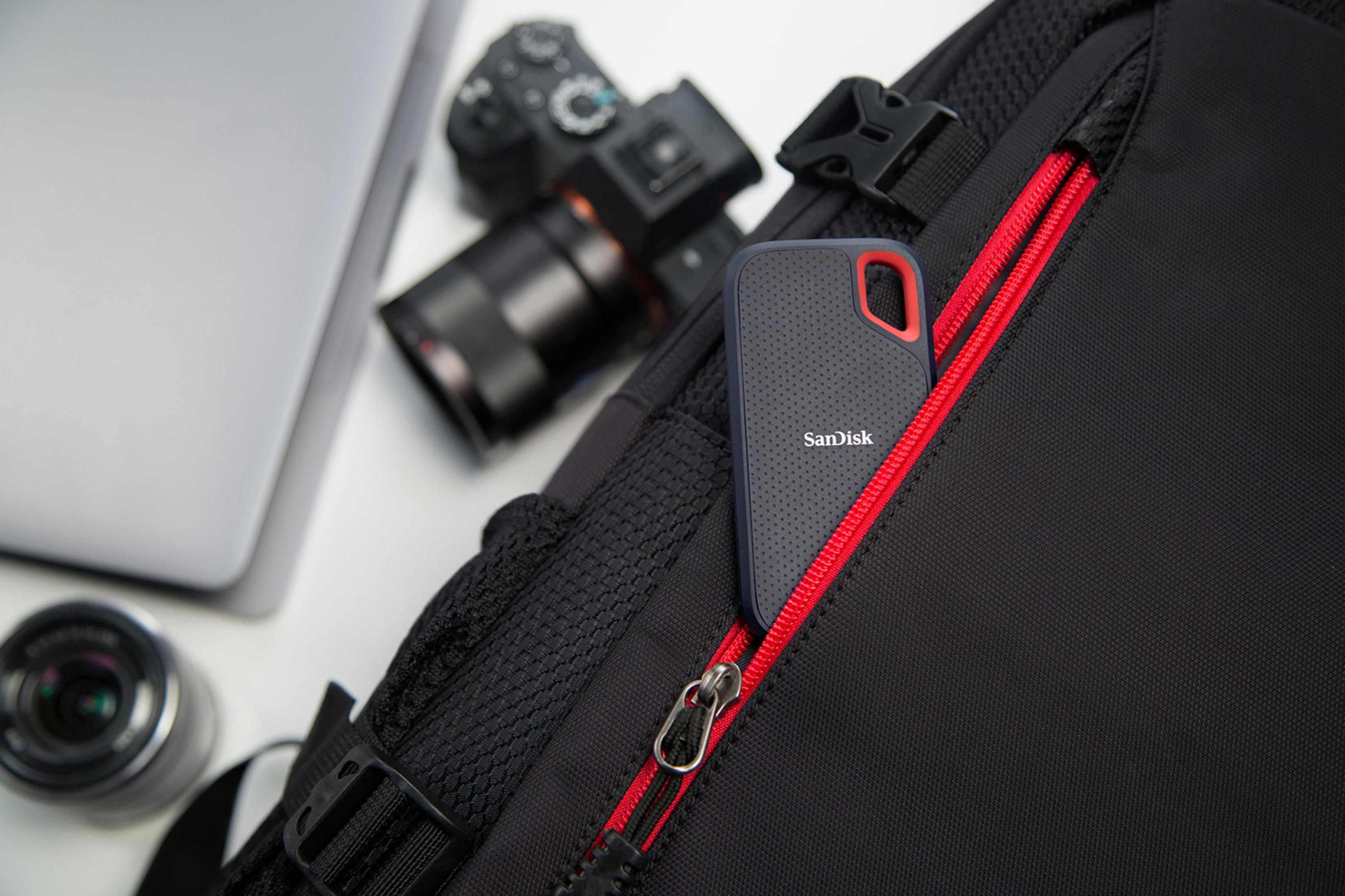 Borsa nera con un disco rigido esterno SanDisk nella sua tasca foderata di rosso.