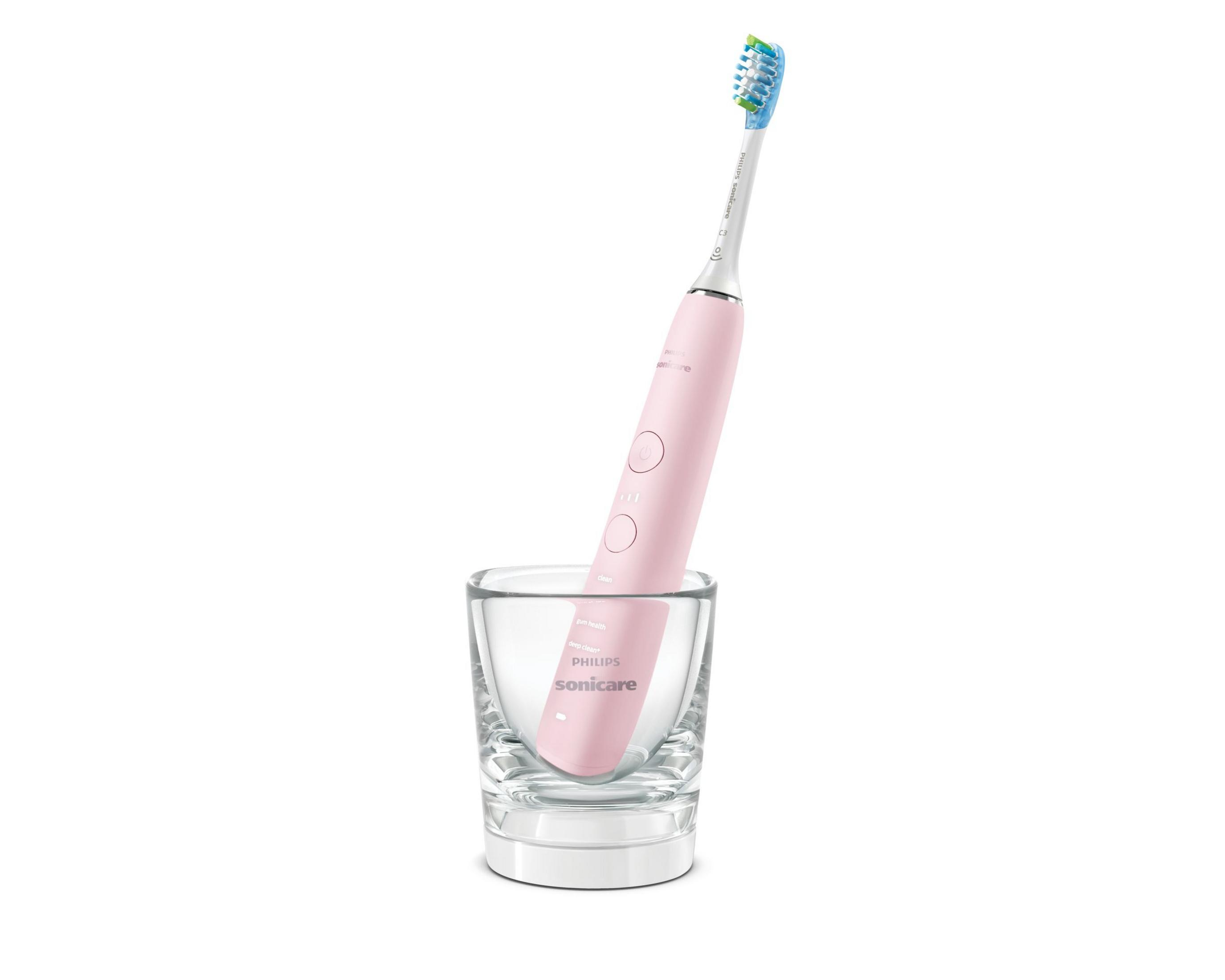 Spazzolino elettrico rosa in un bicchiere. Lo spazzolino è in posizione verticale.