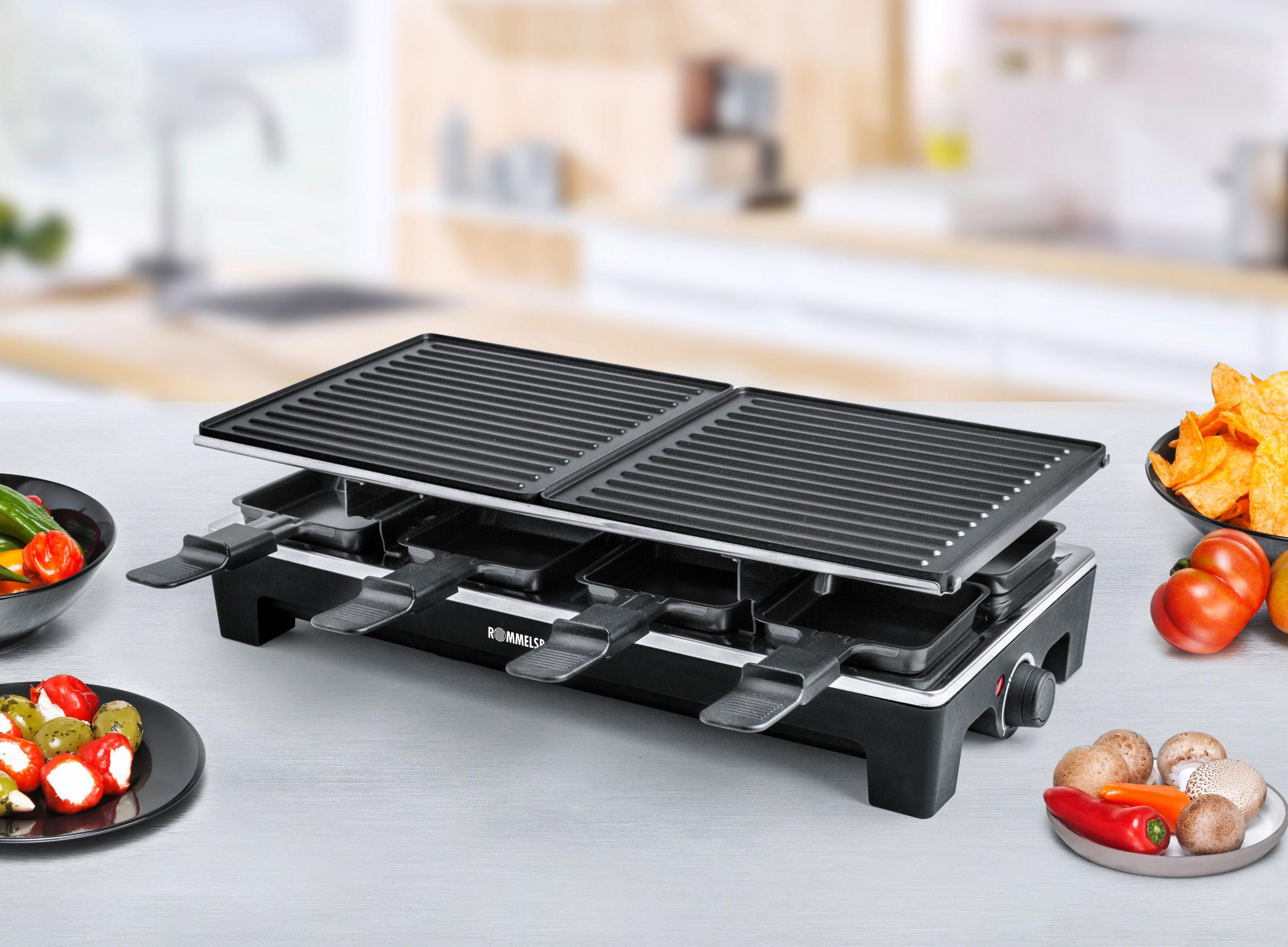 Grill do raclette z czarnymi powierzchniami do gotowania, metalowymi uchwytami i pokrętłem sterowania. Żywność otacza grill na stole.