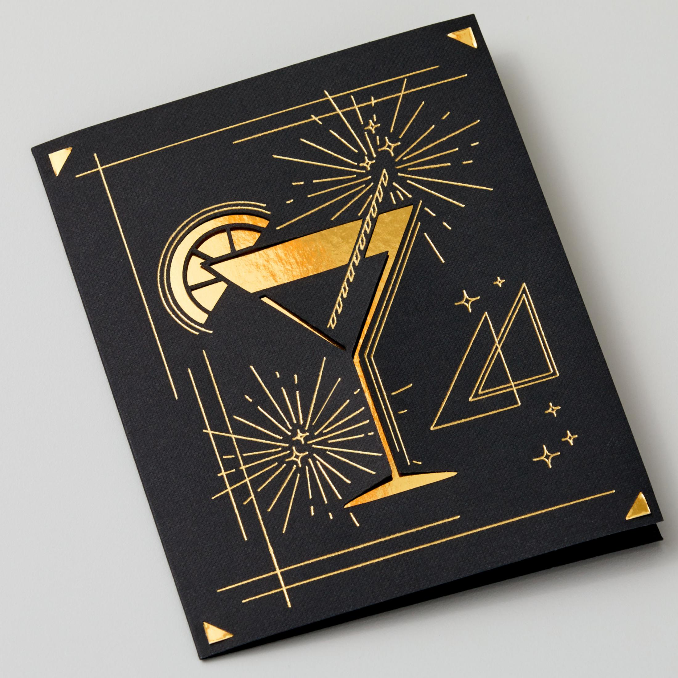 Schwarze Grußkarte mit einer goldenen Cocktail-Illustration und Feuerwerk-Design auf grauem Hintergrund.