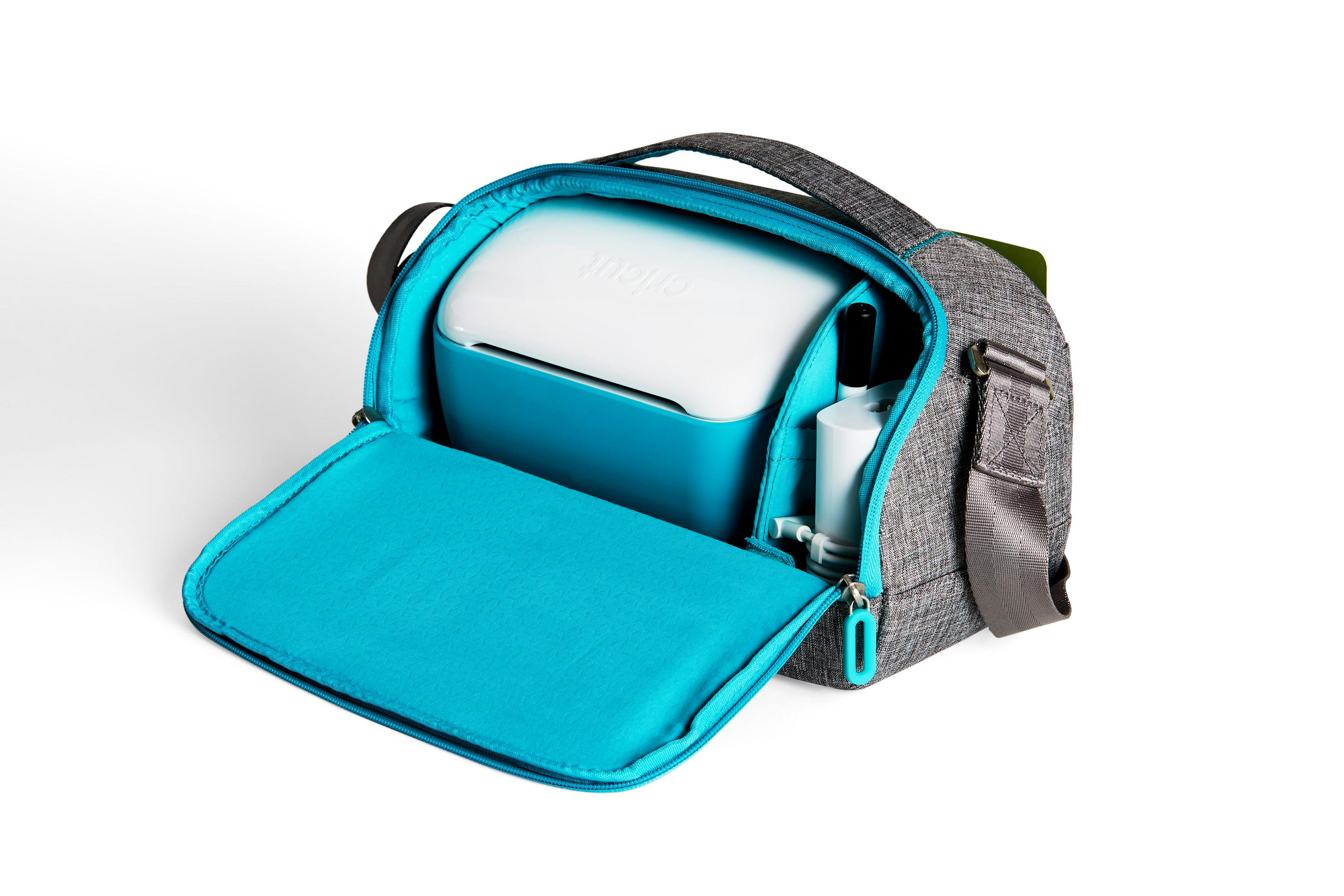 Geöffnete graue Tasche mit teal-farbenem Innenraum. Ein weißes Gerät ist darin.
