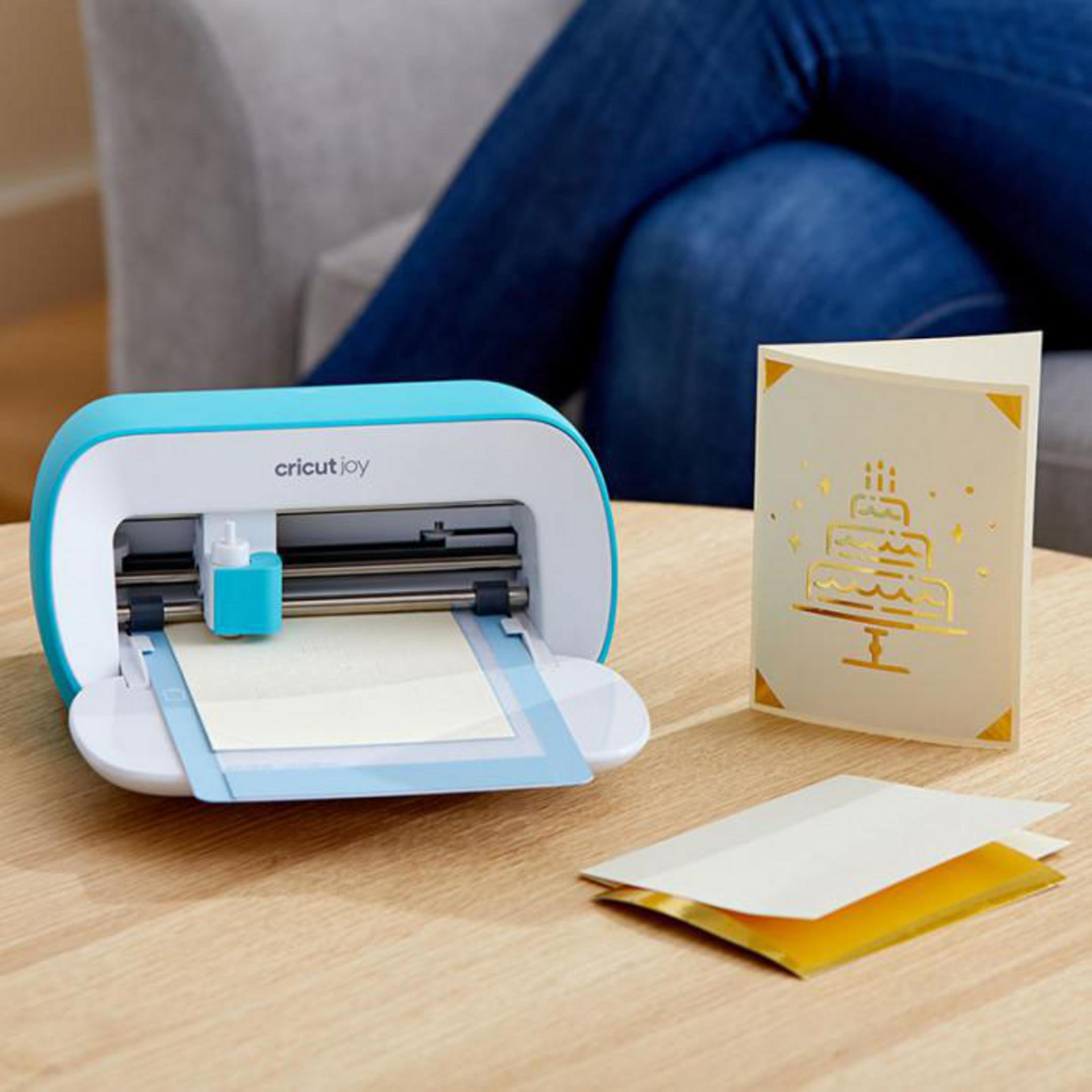 Eine blau-weiße Cricut Joy Maschine mit einer Karte und zwei weiteren Karten.